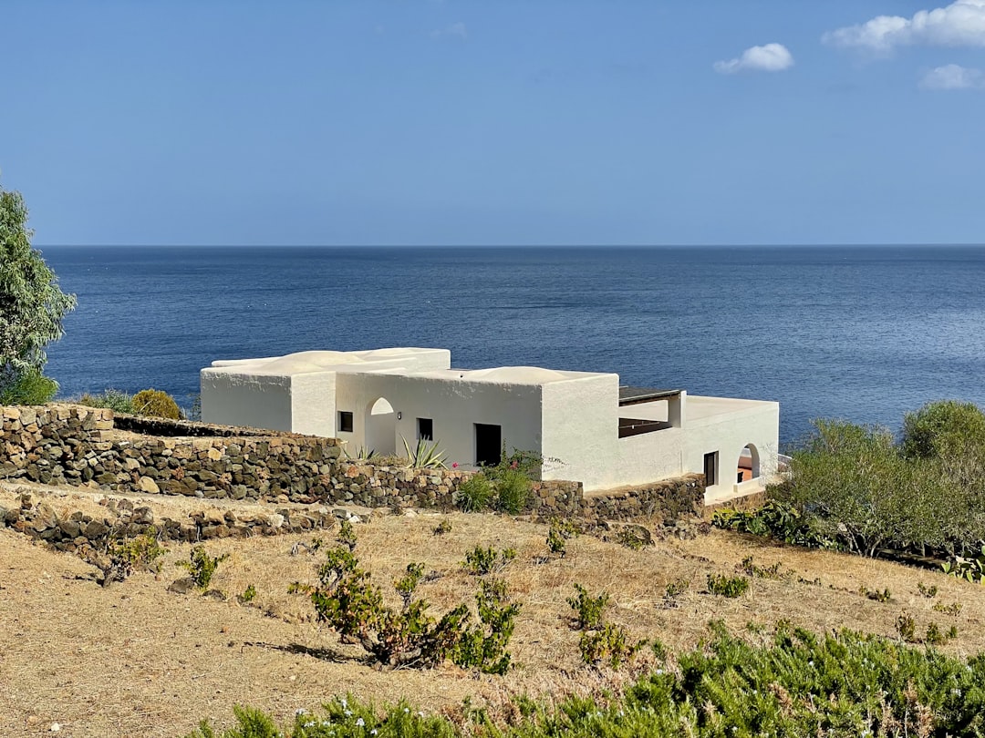A white house sitting on top of a hill next to the ocean,