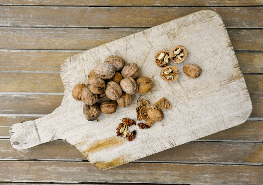 Whole walnuts and cracked halves on a pale wooden board