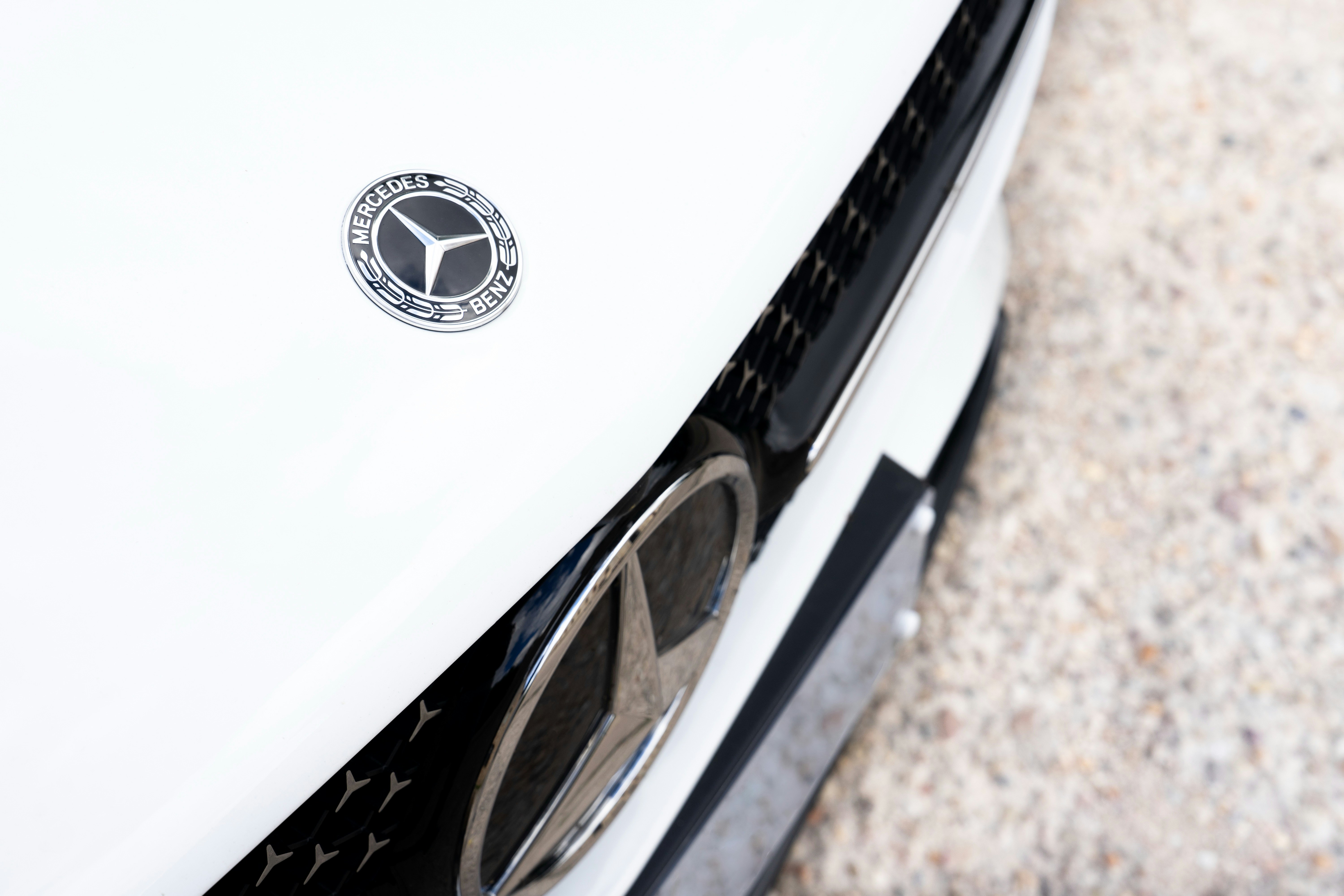 A close up of a mercedes emblem on a white car