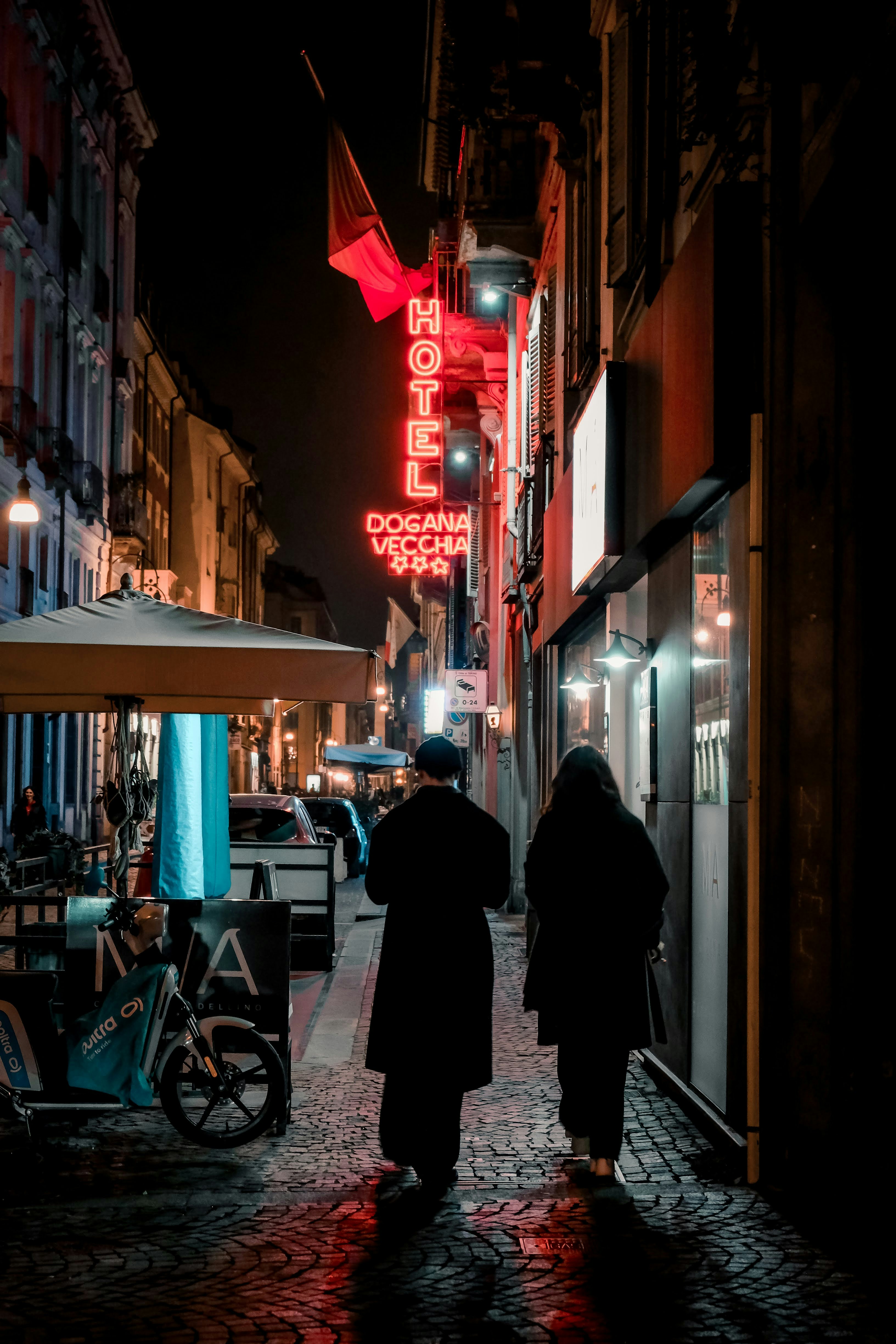 A couple of people walking down a street at night