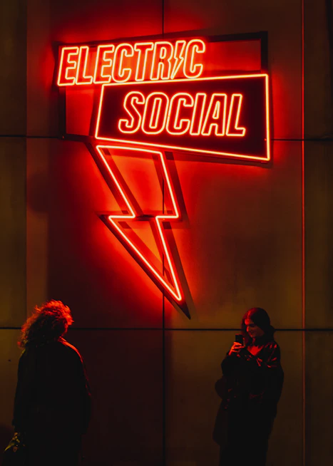 Two people standing in front of a neon sign