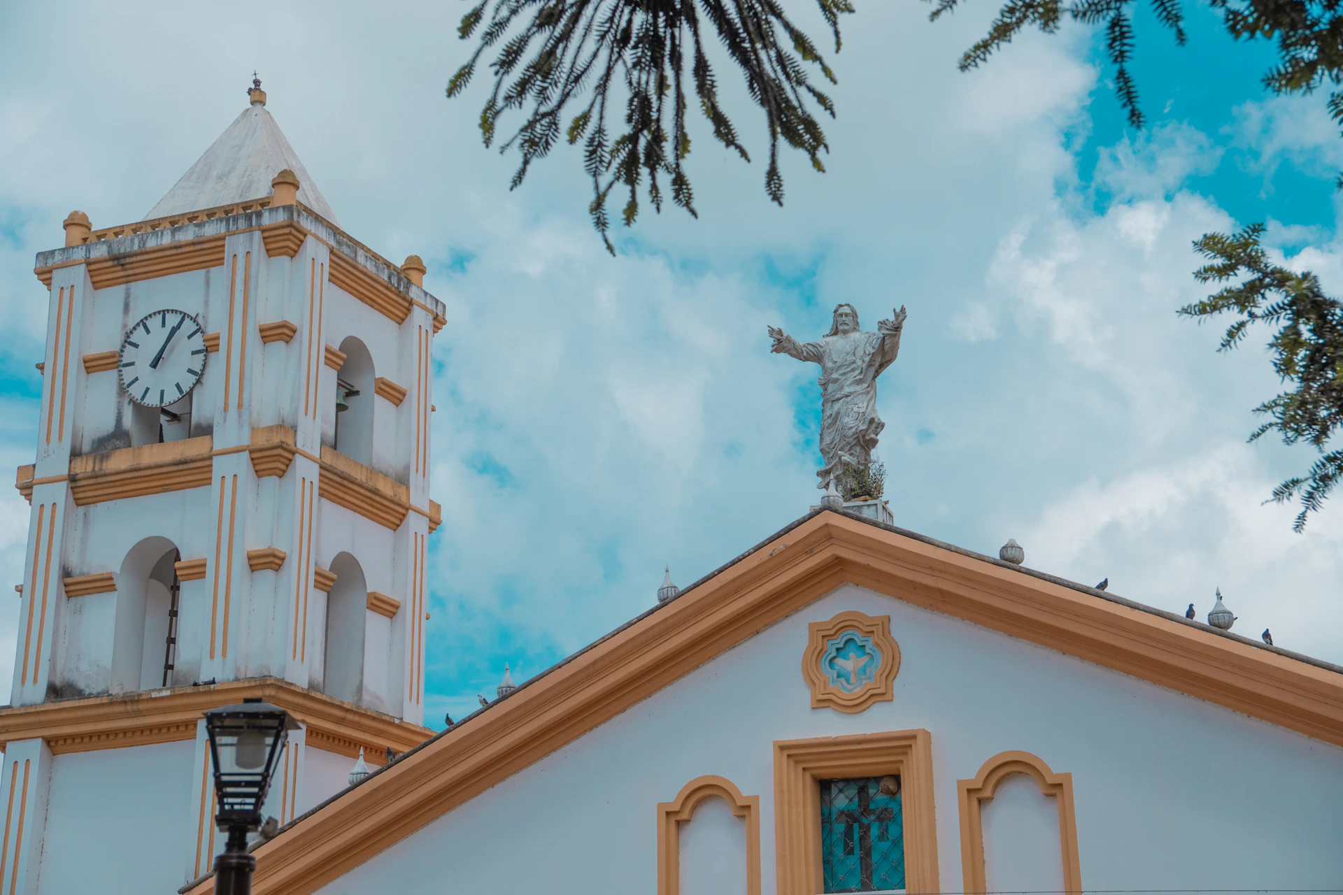A church with a clock tower and a statue on top