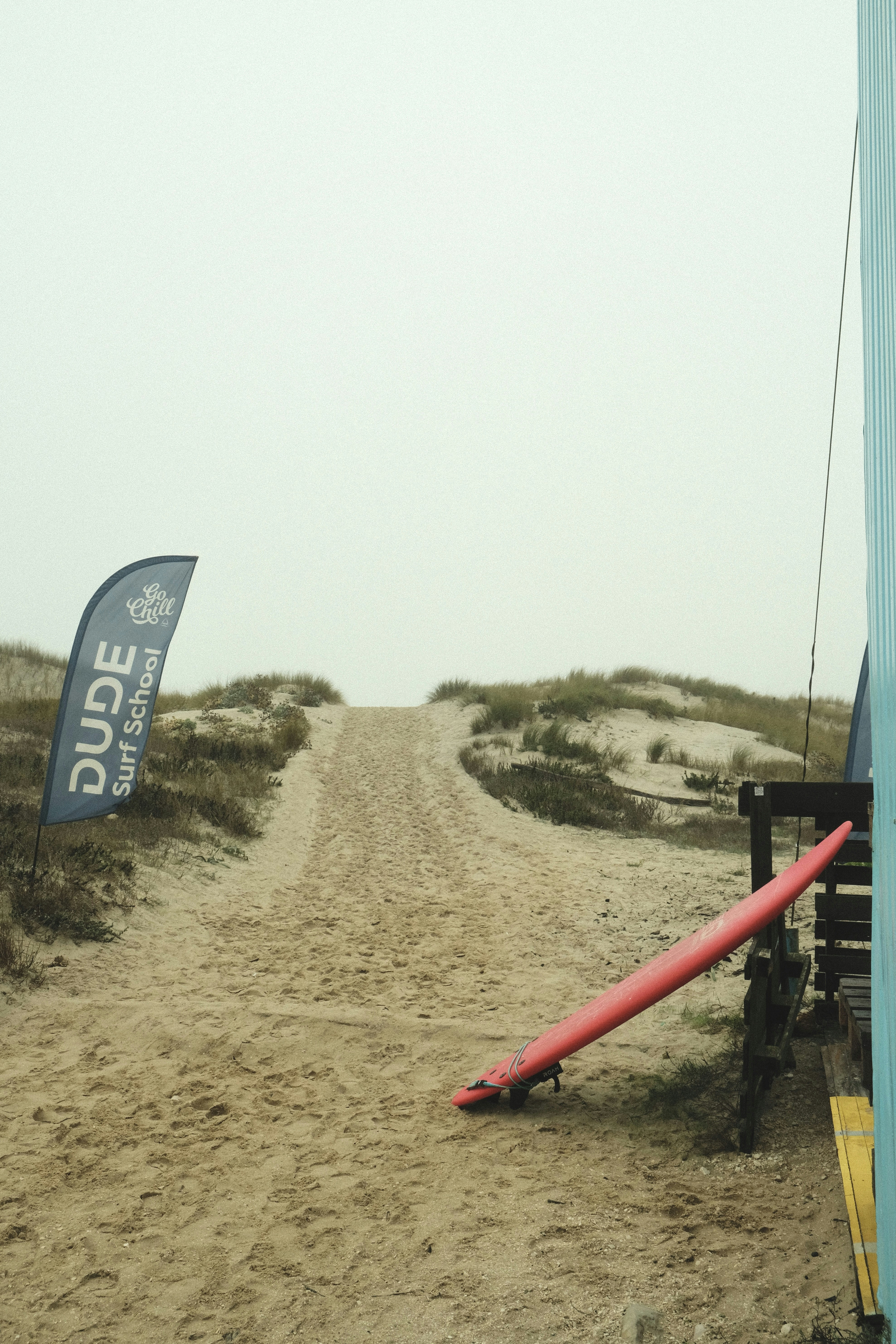 A surfboard leaning against a pole on a beach