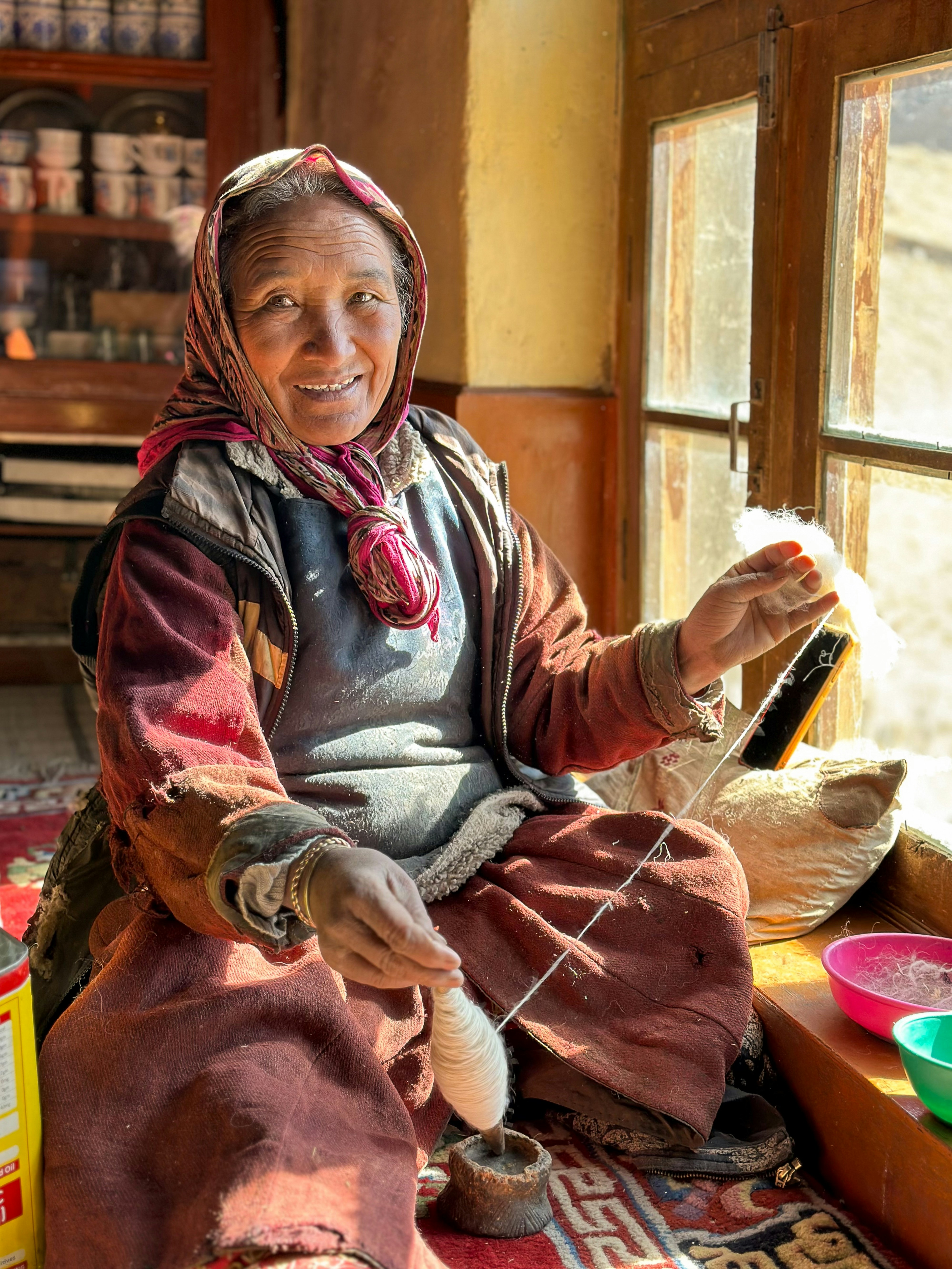 A woman sitting on the floor weaving a piece of fabric