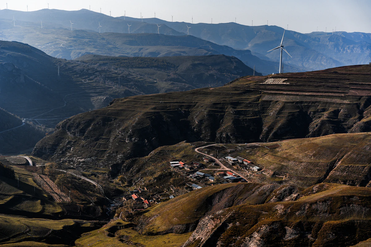 Terraced brown hills, a village and wind turbines on Matian Mountain in Yu County, Zhangjiakou