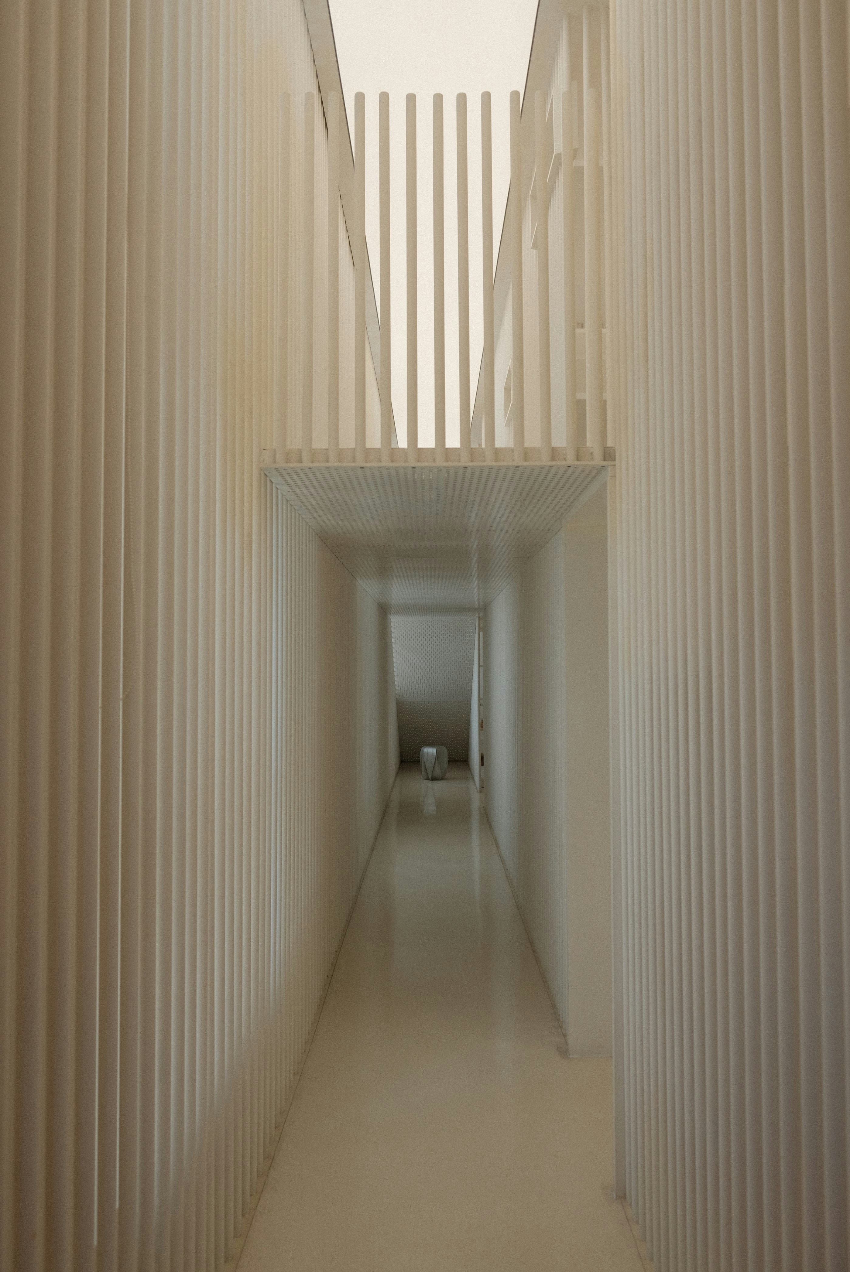 A long hallway with white walls and a white staircase