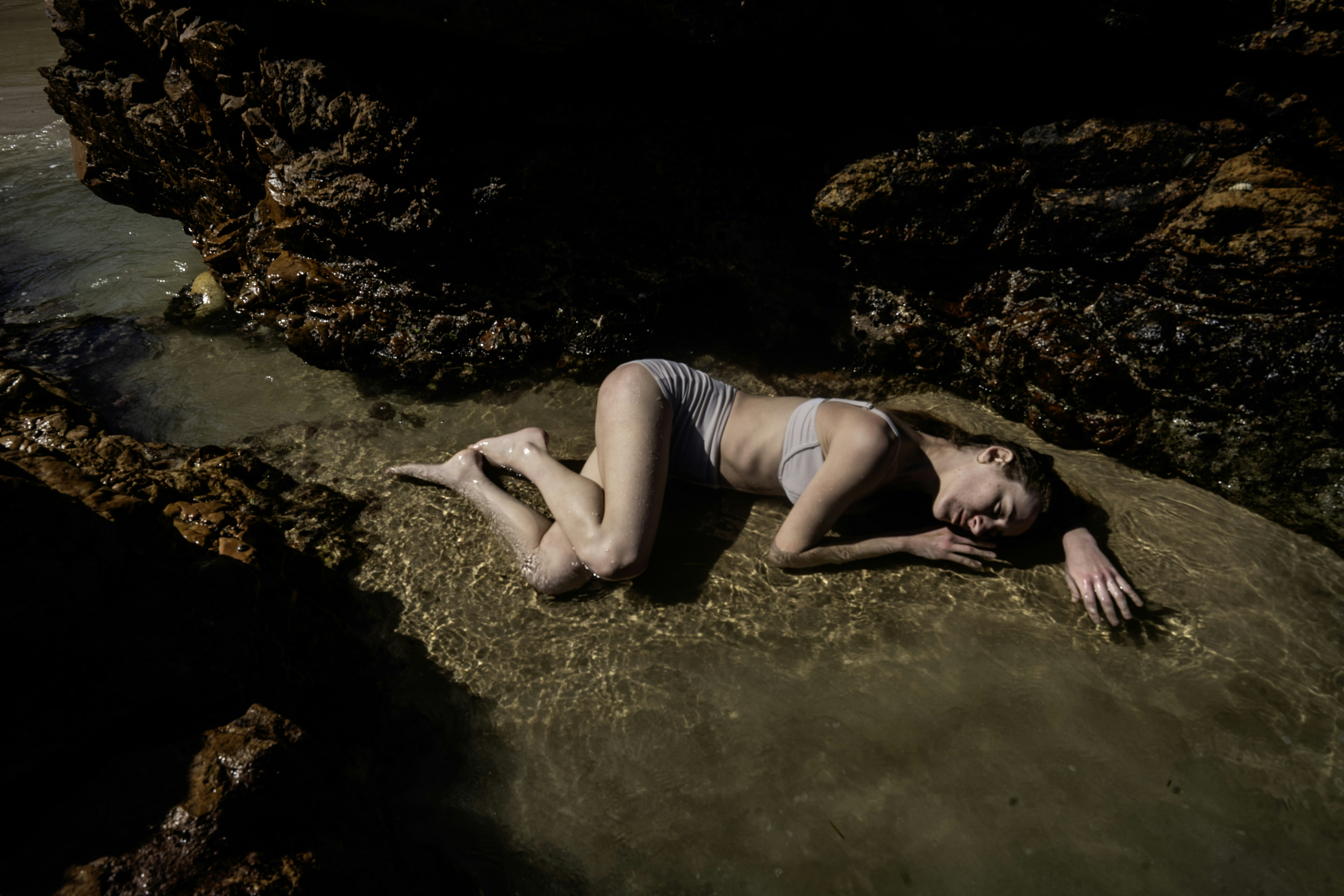 A naked woman laying on a rocky beach