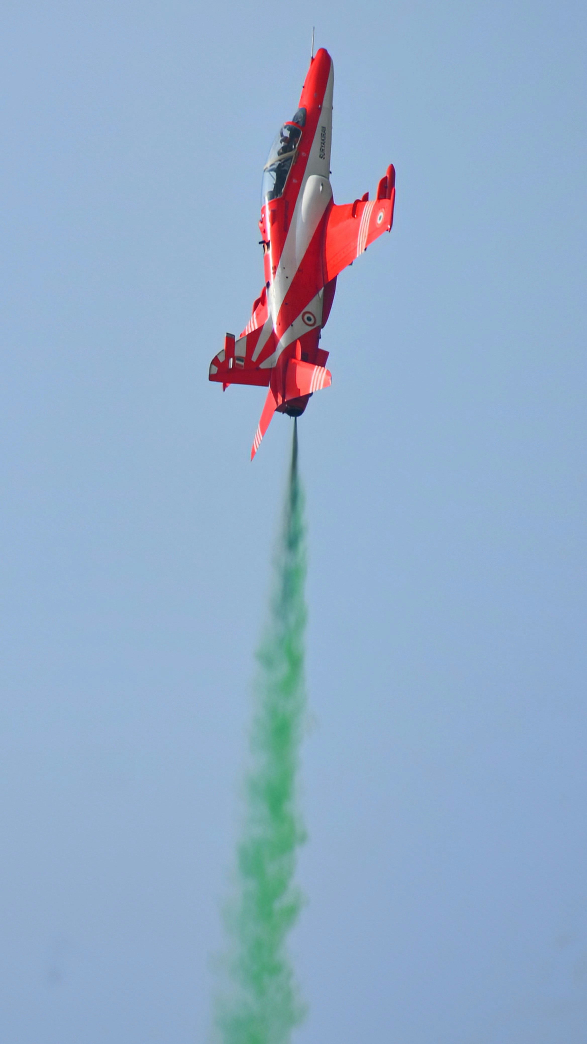 A red and white jet flying through a blue sky
