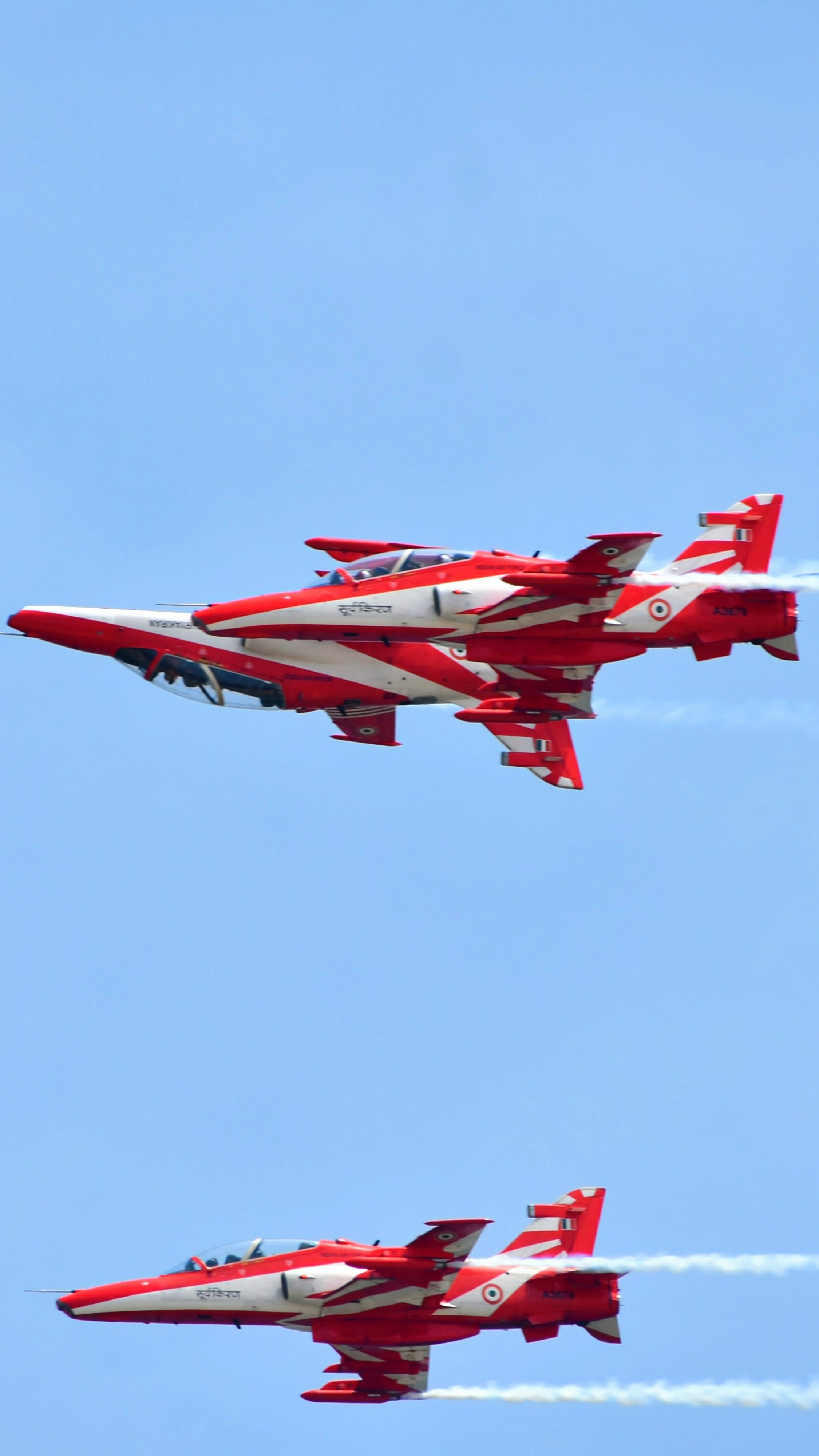 Two red and white jets flying in the sky