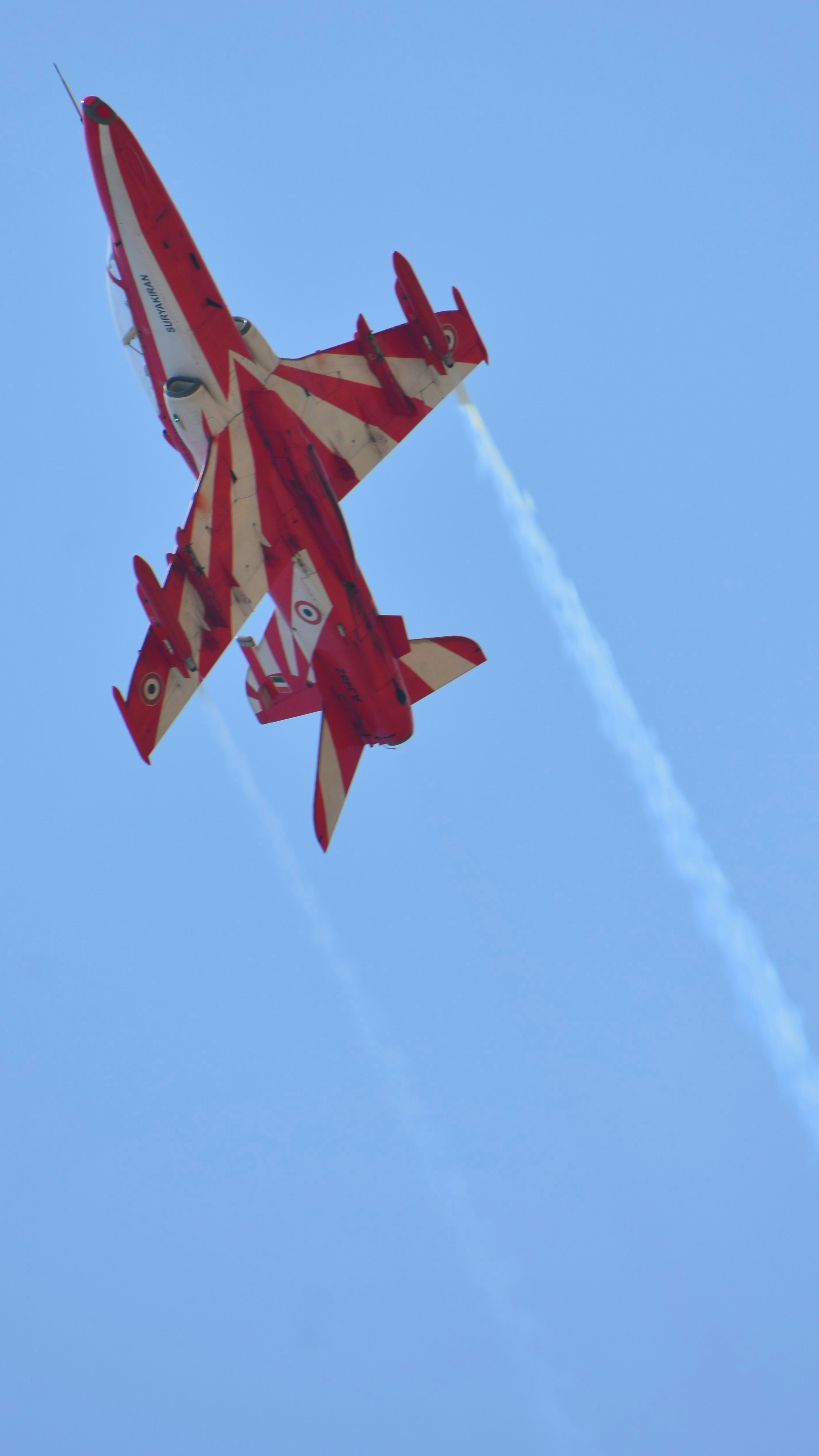 A red and white jet flying through a blue sky