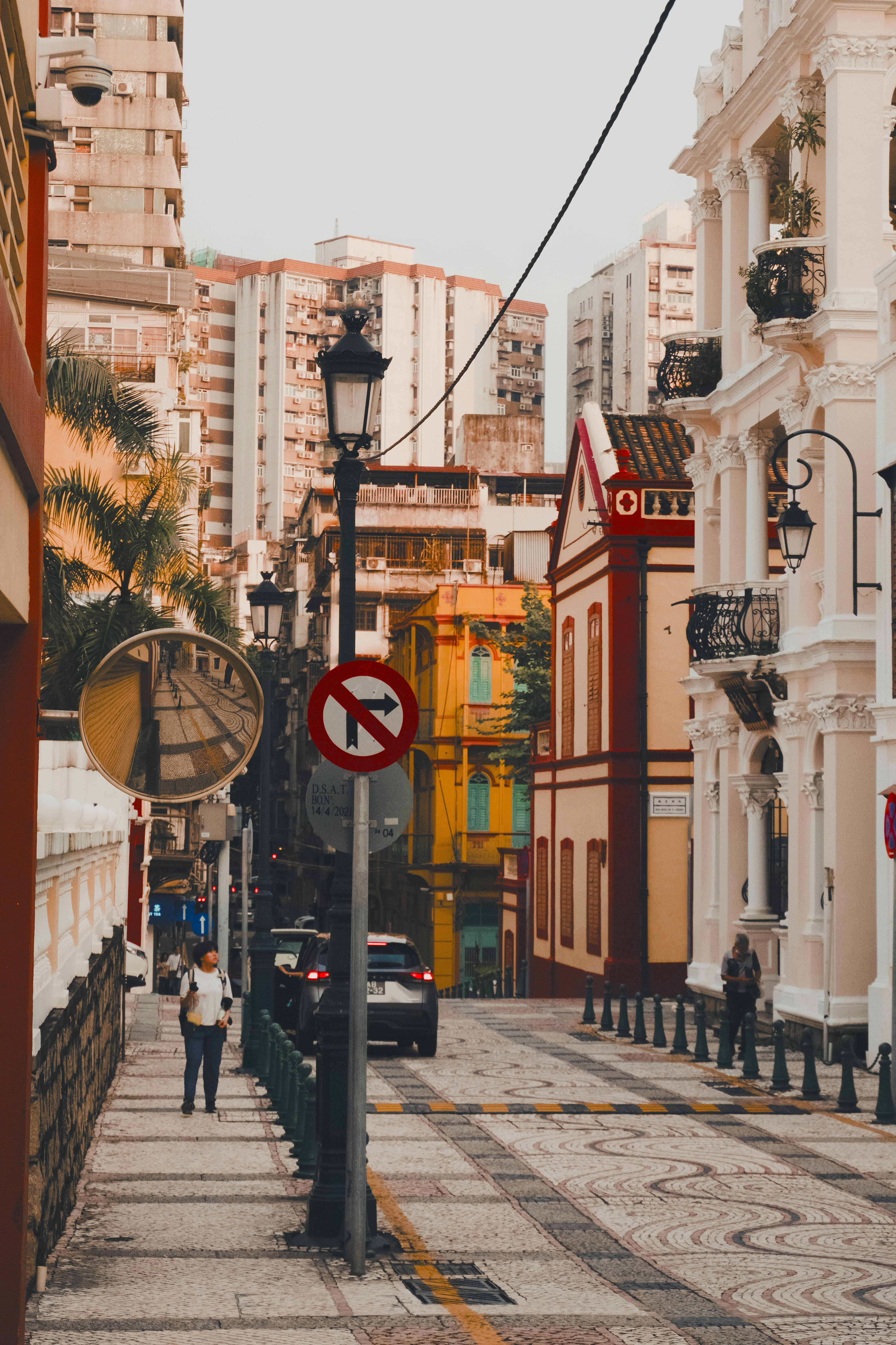 A narrow city street with a no left turn sign