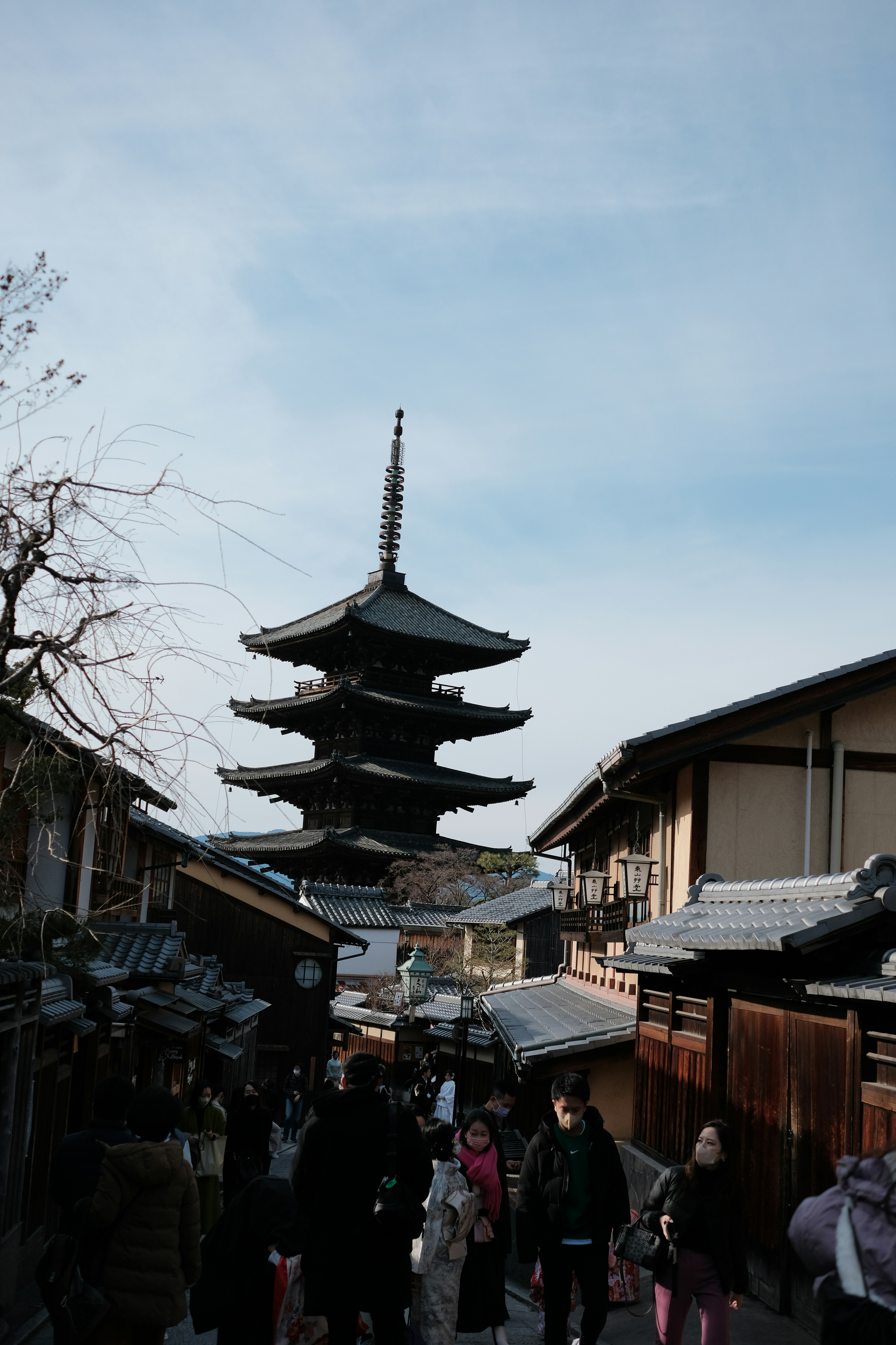 A group of people walking down a street next to tall buildings
