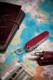 A red pocket knife and a wallet on a map