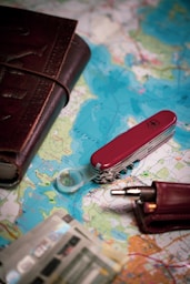 A red pocket knife and a wallet on a map