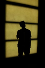 A silhouette of a person standing in front of a window