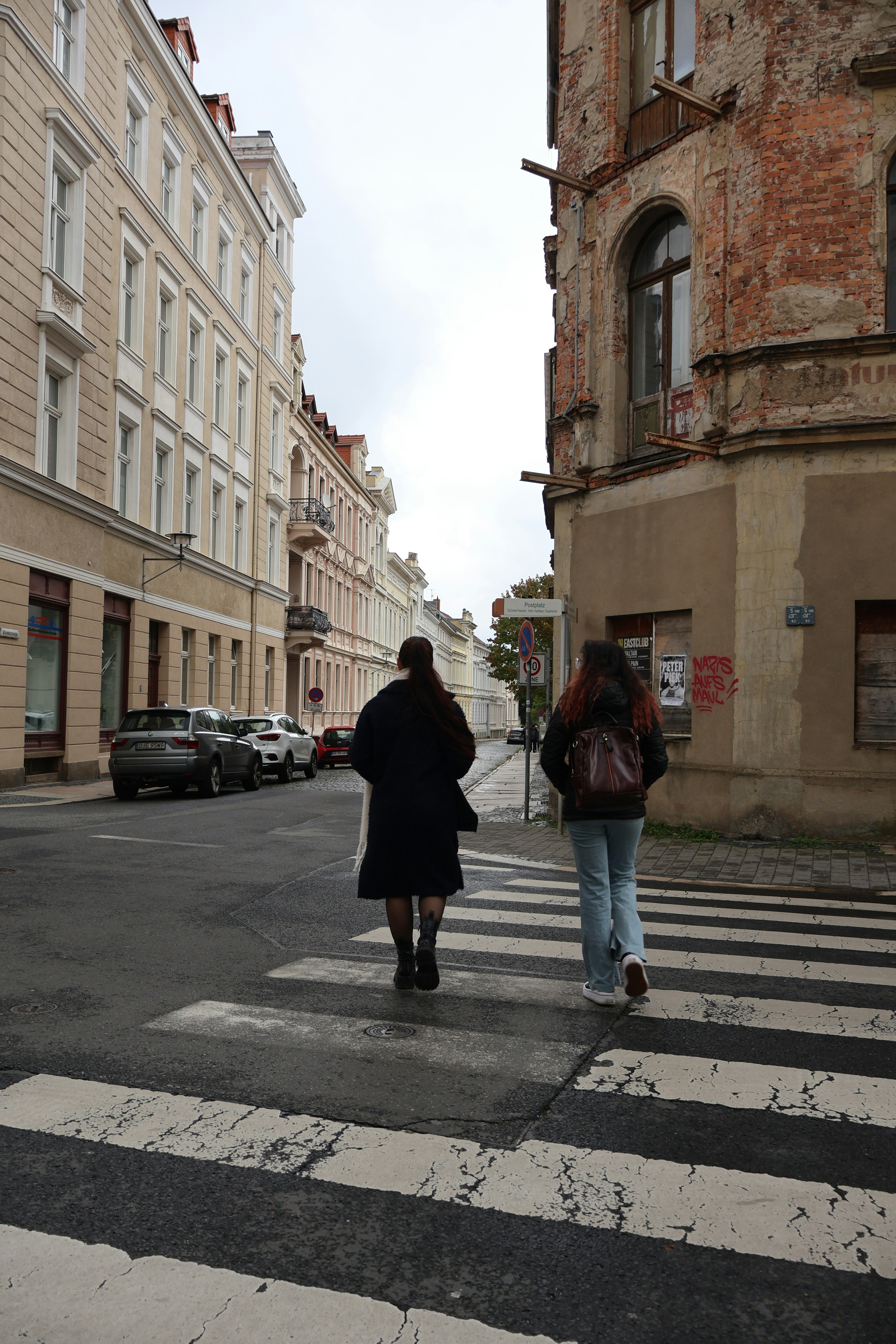 A couple of people walking across a cross walk