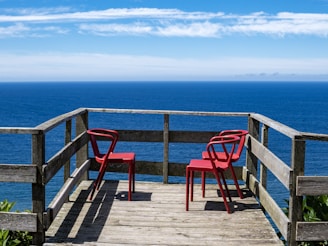 Two red chairs sitting on top of a wooden deck