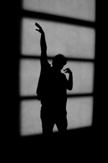 A silhouette of a person standing in front of a window
