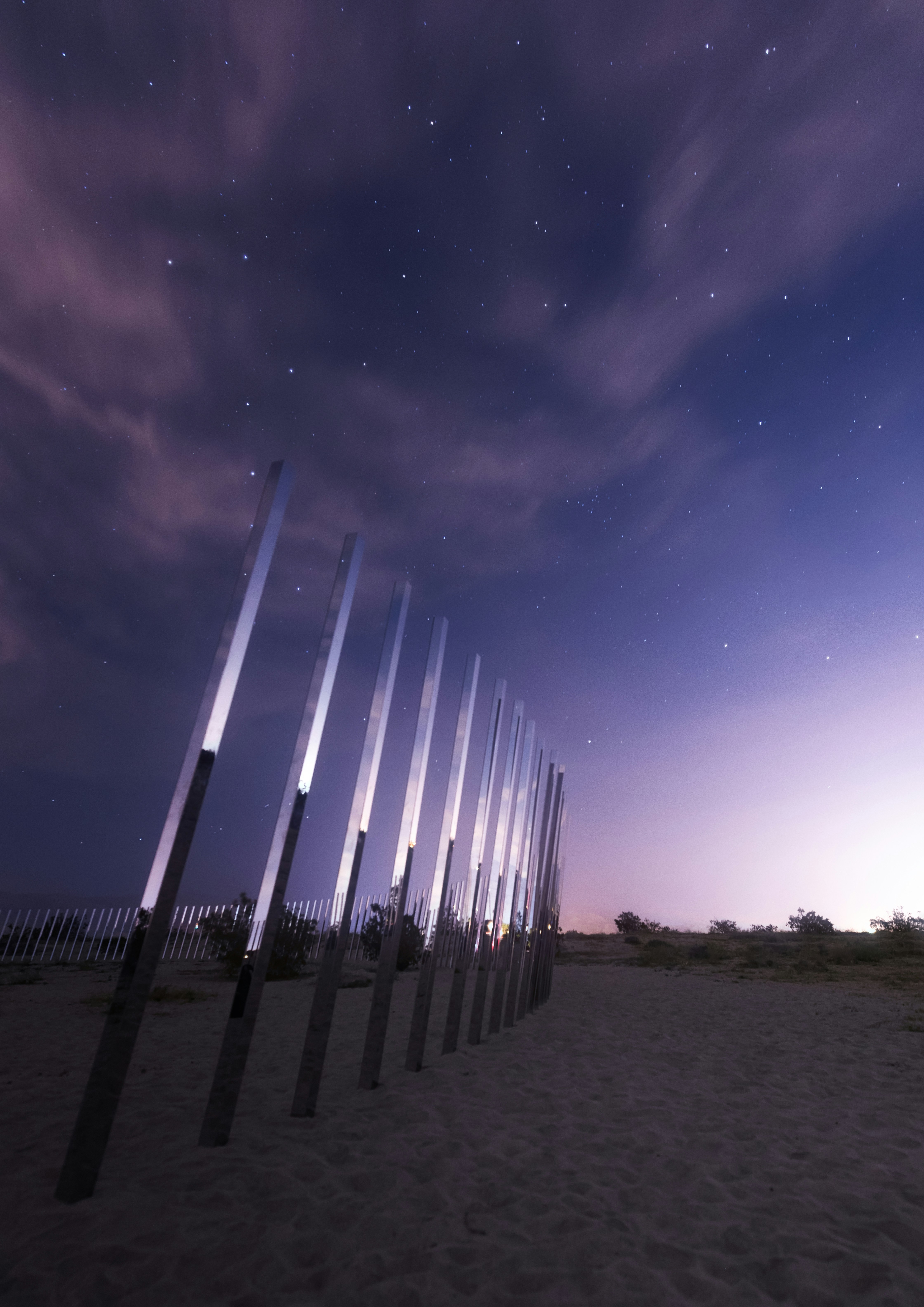 A row of poles sitting on top of a sandy beach