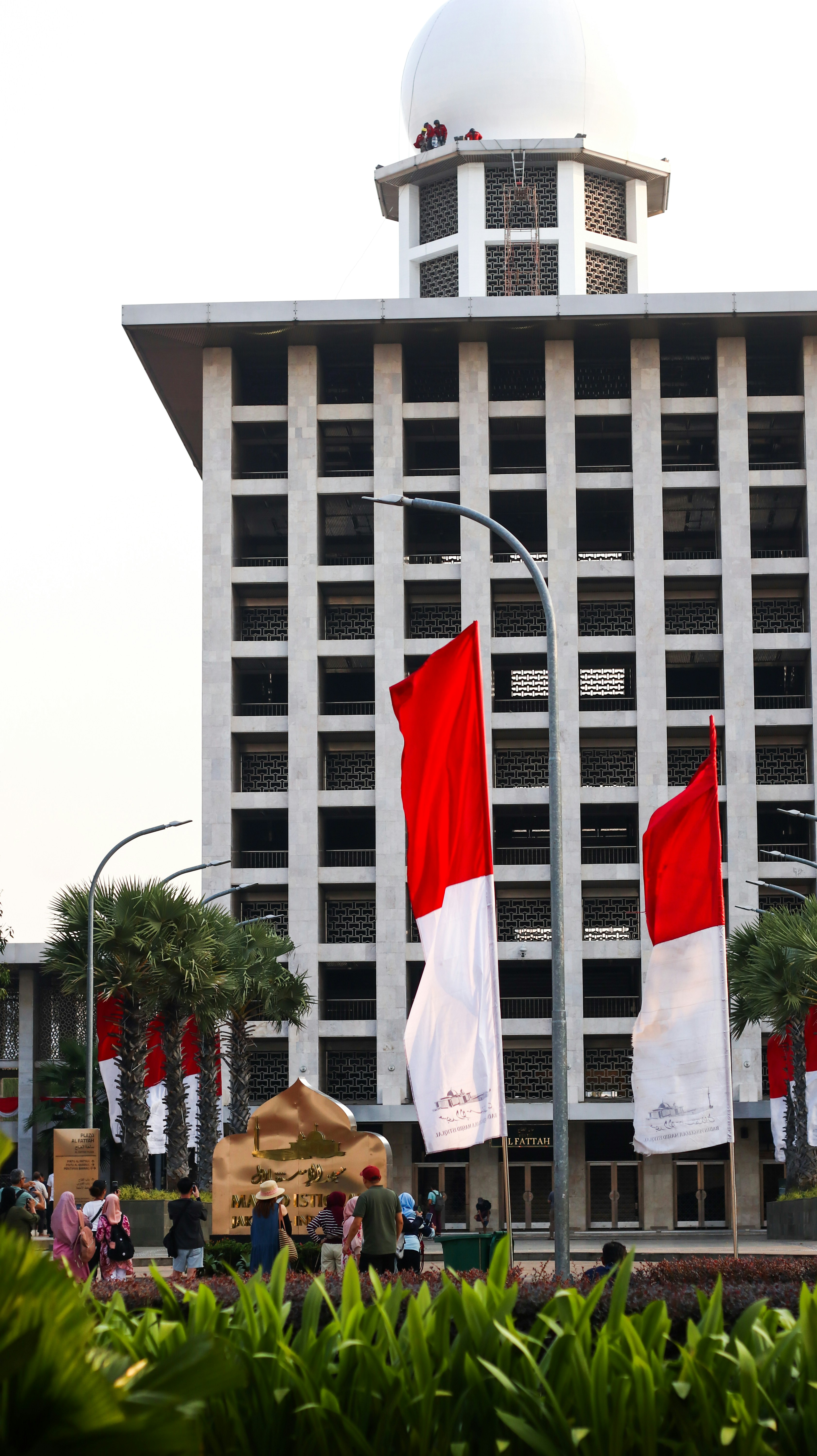 A tall building with a white dome and red and white flags in front of it