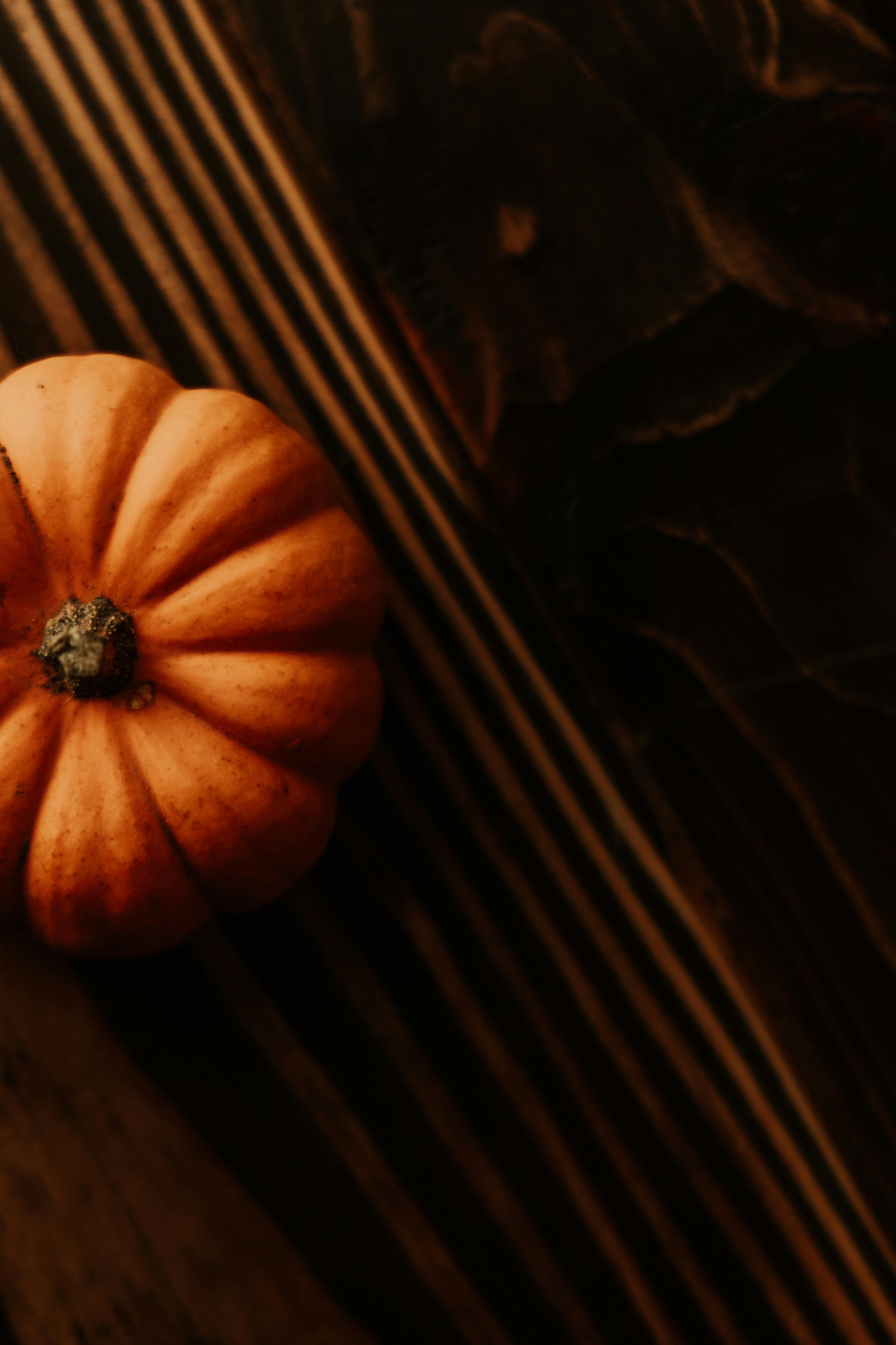A small orange pumpkin sitting on top of a wooden table