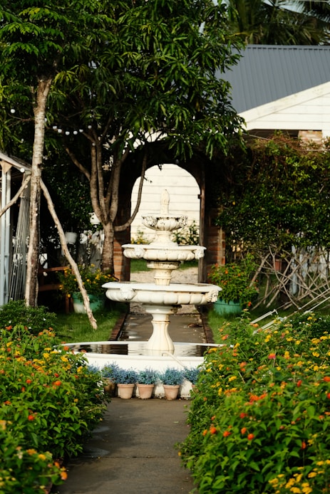 A garden with a fountain surrounded by flowers