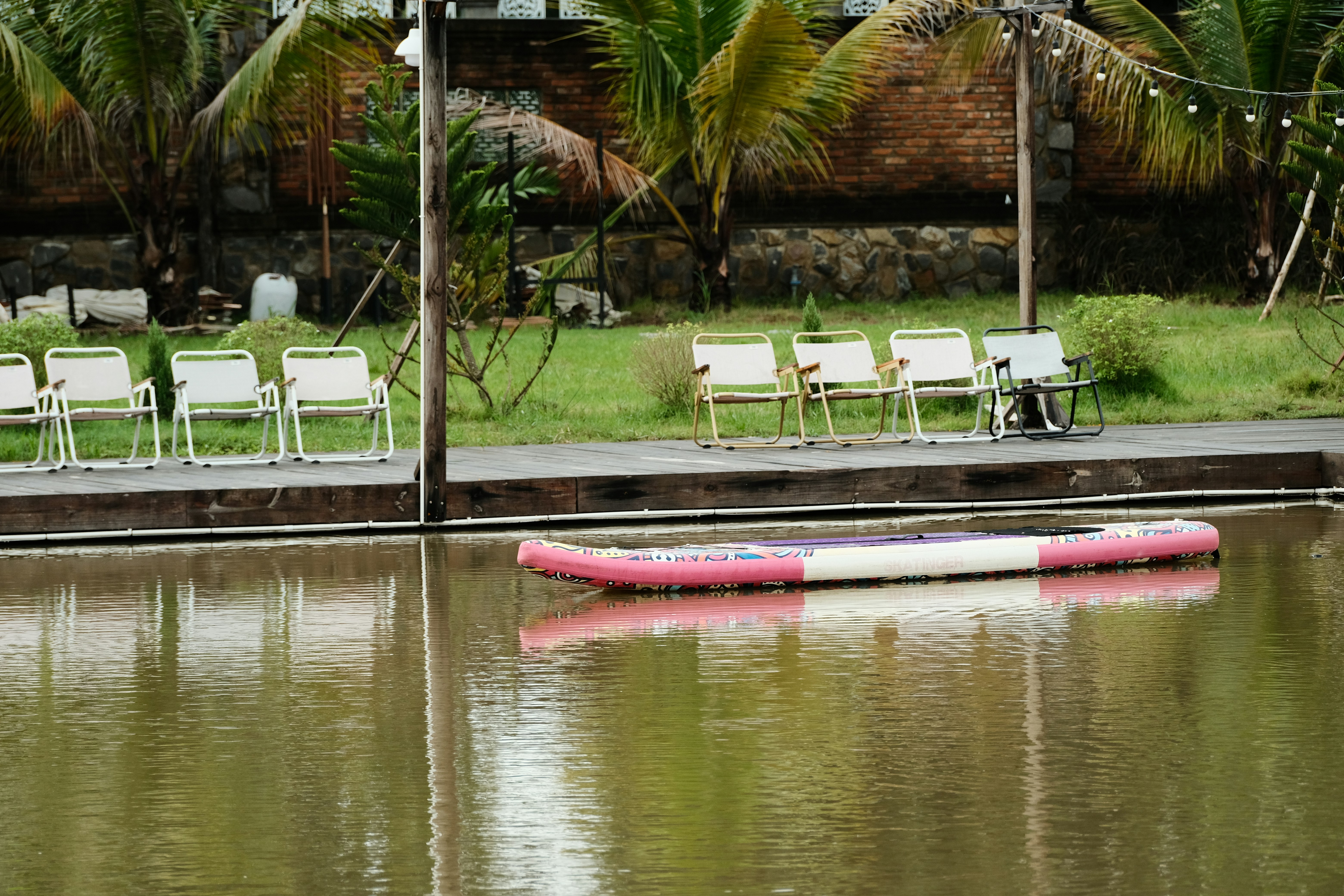 A row of lawn chairs sitting next to a body of water photo – Free ...