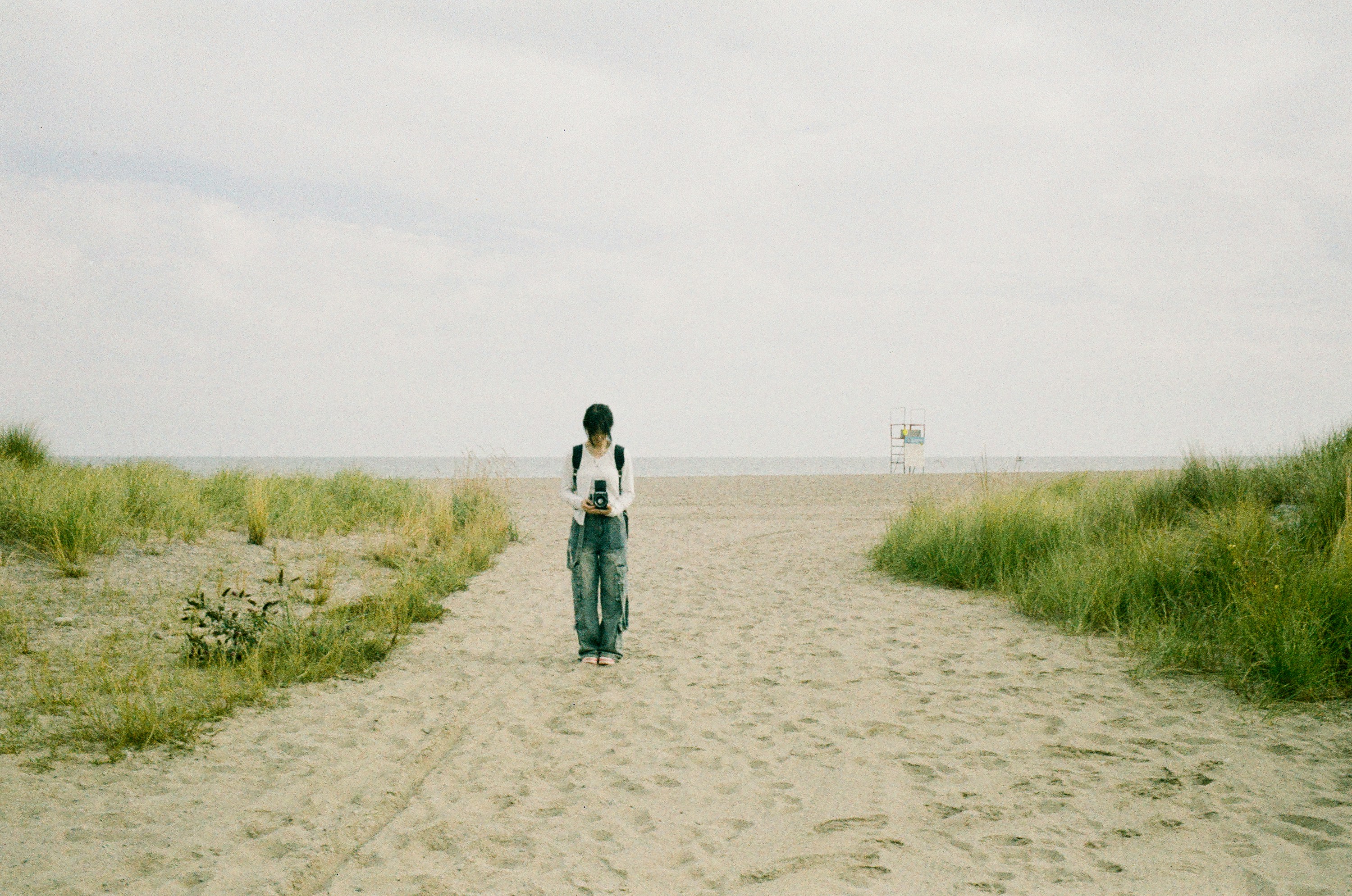 A person walking down a dirt road in the middle of a field
