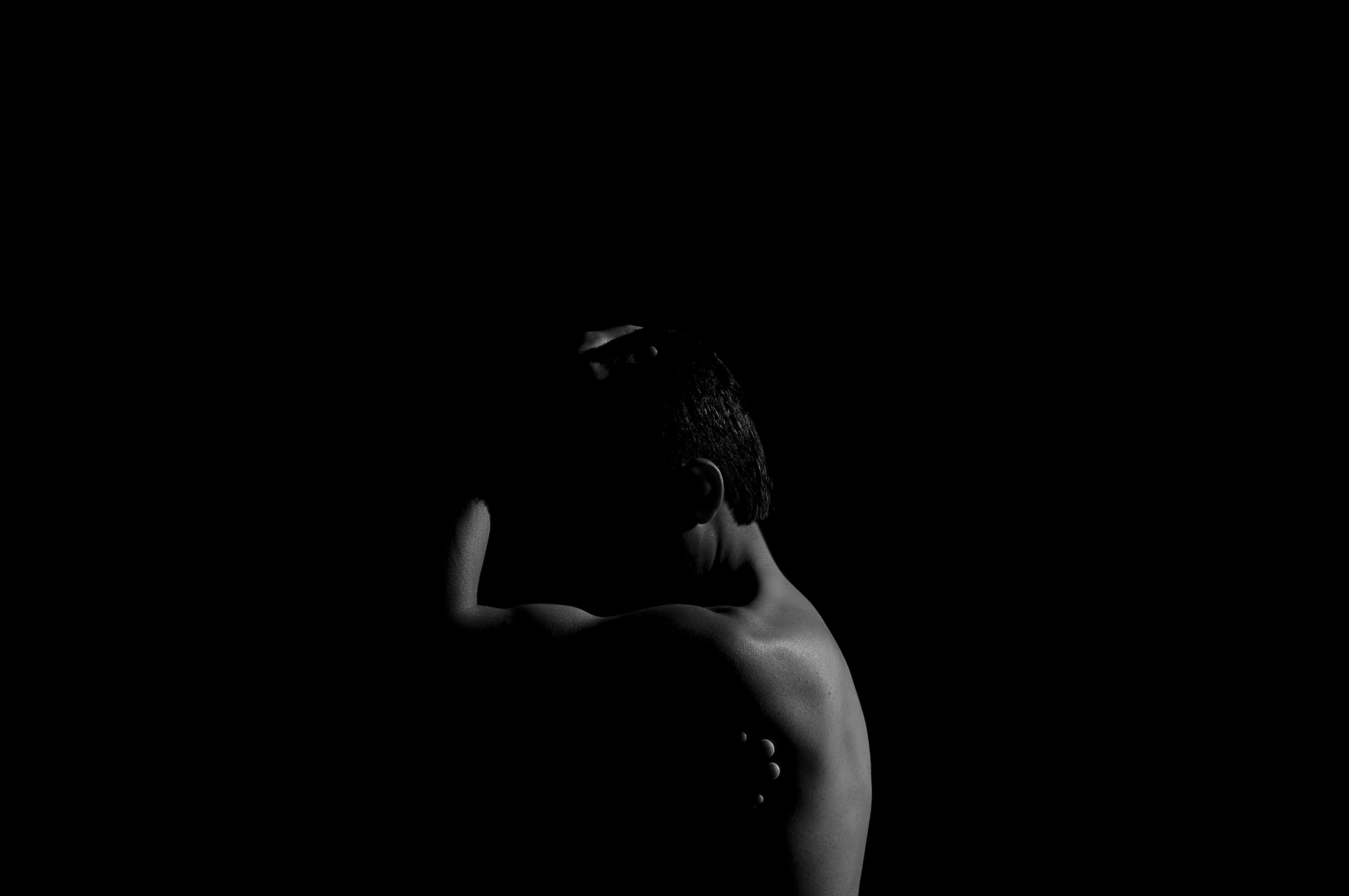A naked woman standing in the dark with her back to the camera