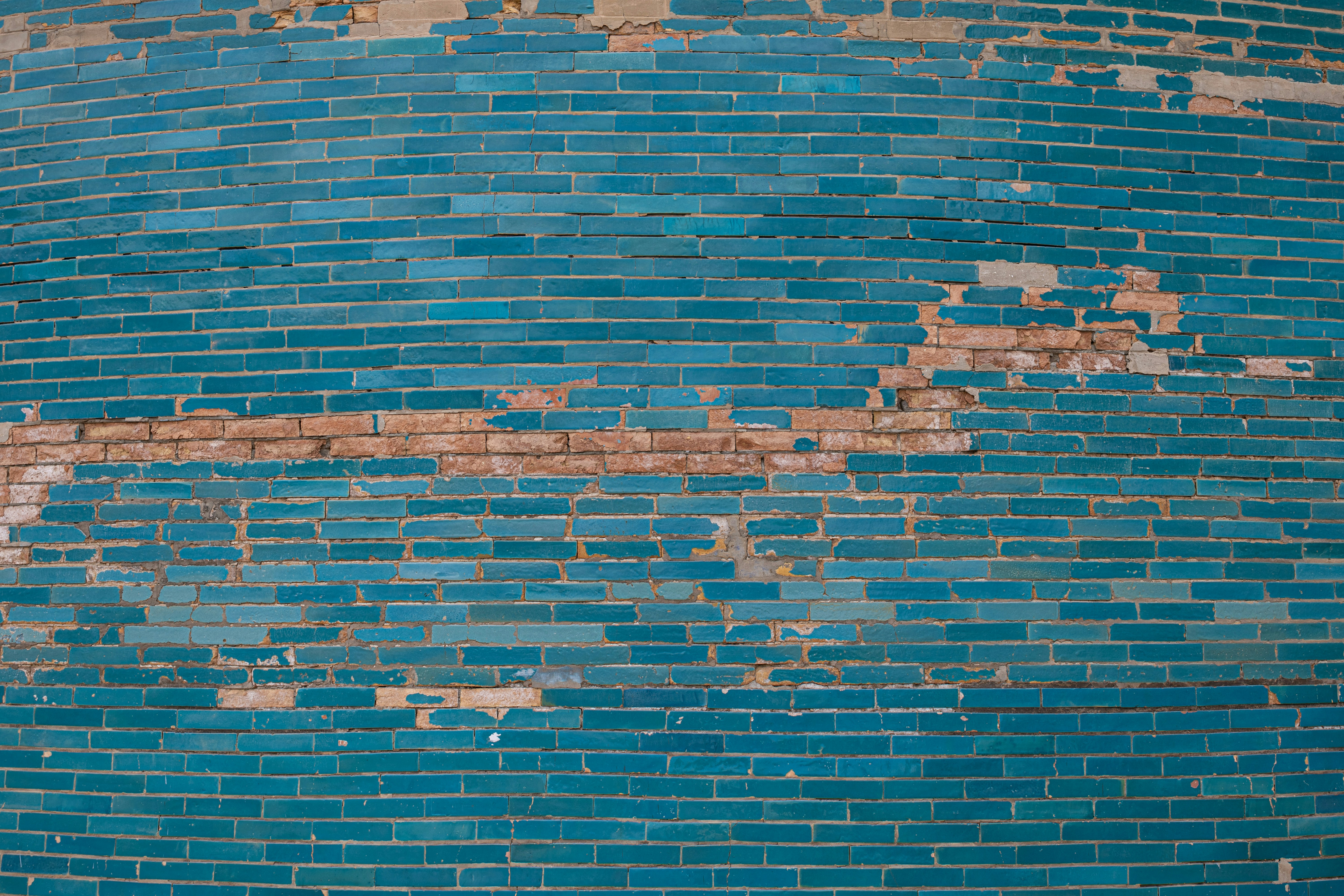 A blue brick wall with peeling paint on it
