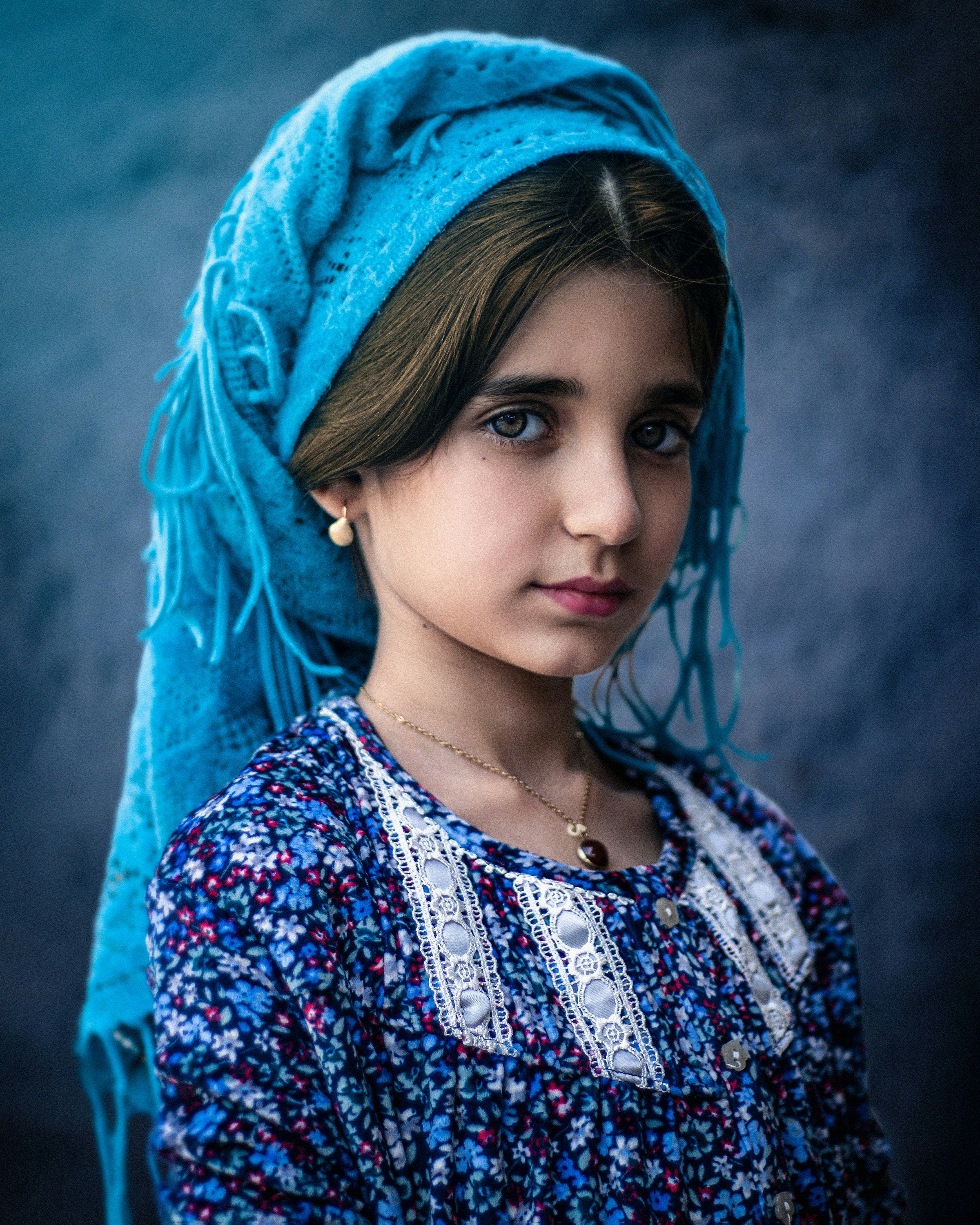 A young girl with a blue shawl on her head
