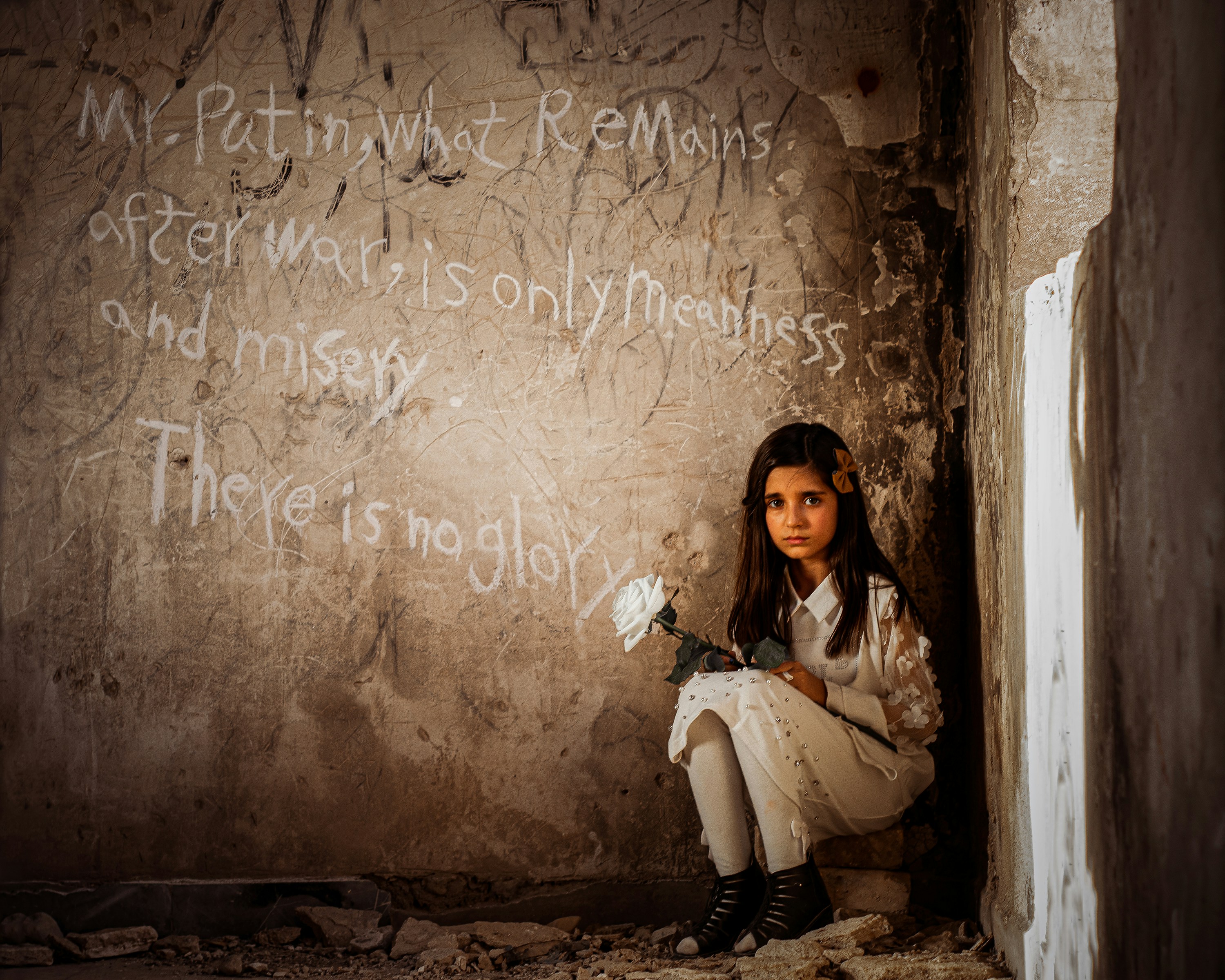 A young girl sitting in a corner with graffiti on the wall