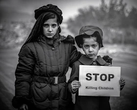 Two children holding a sign that says stop killing children