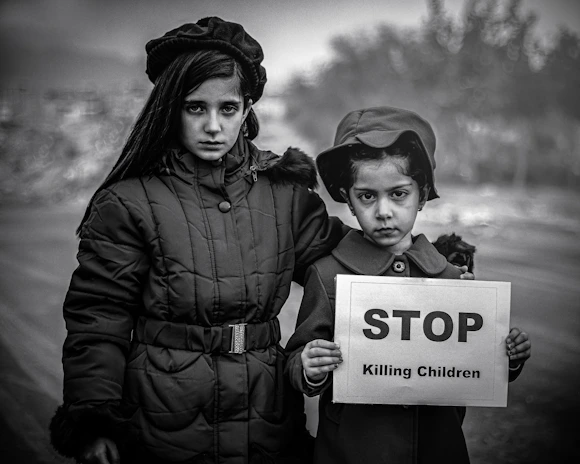 Two children holding a sign that says stop killing children