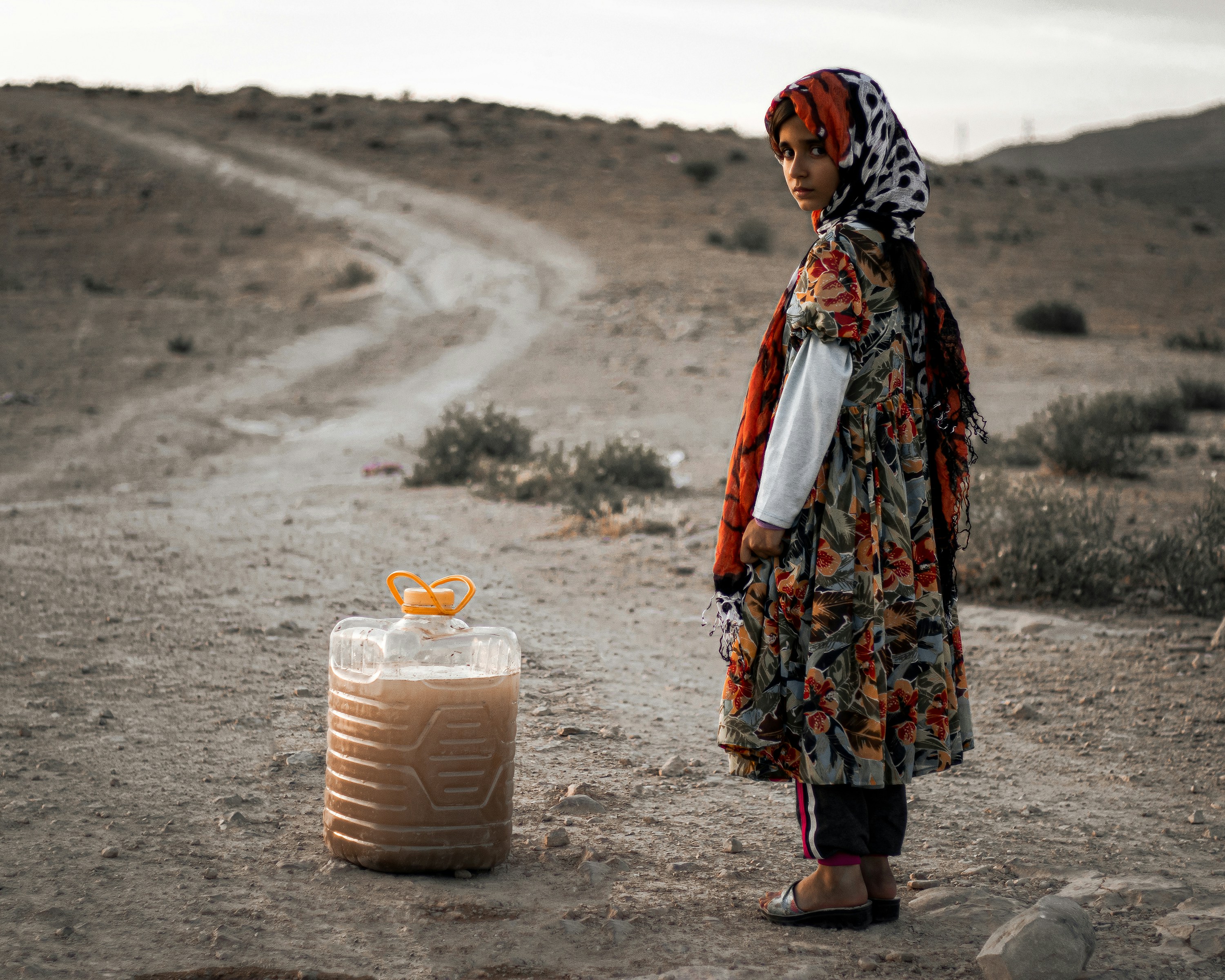A woman standing in the middle of a dirt road