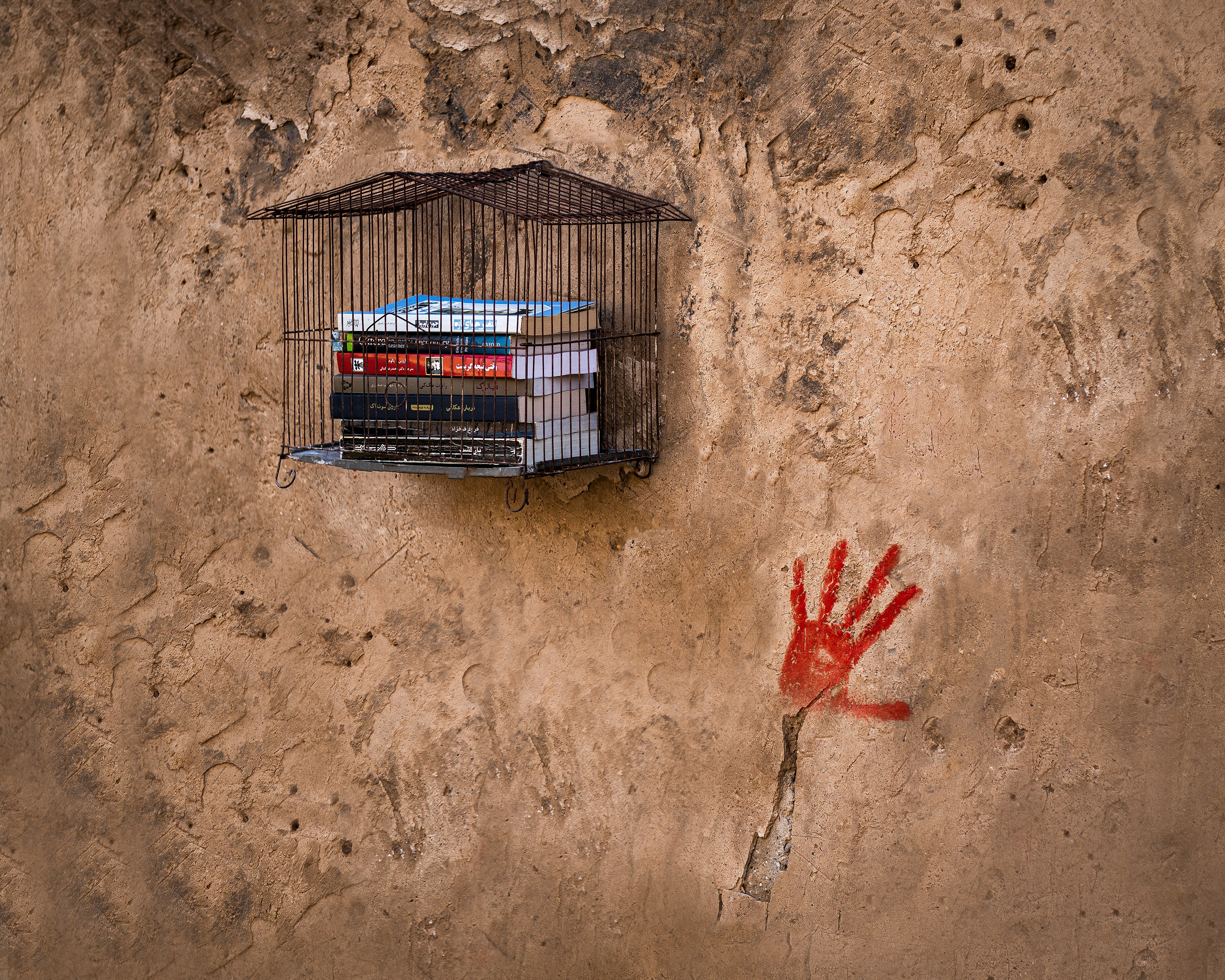 A birdcage with a hand painted on the side of it