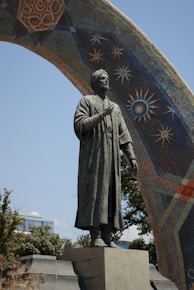 A statue of a man standing next to a large piece of art