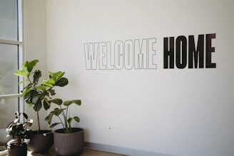 A white wall with a sign that says welcome home