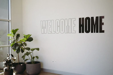 A white wall with a sign that says welcome home