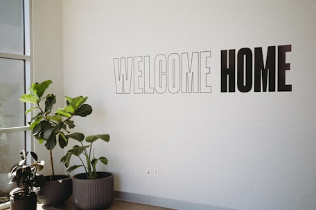 A white wall with a sign that says welcome home