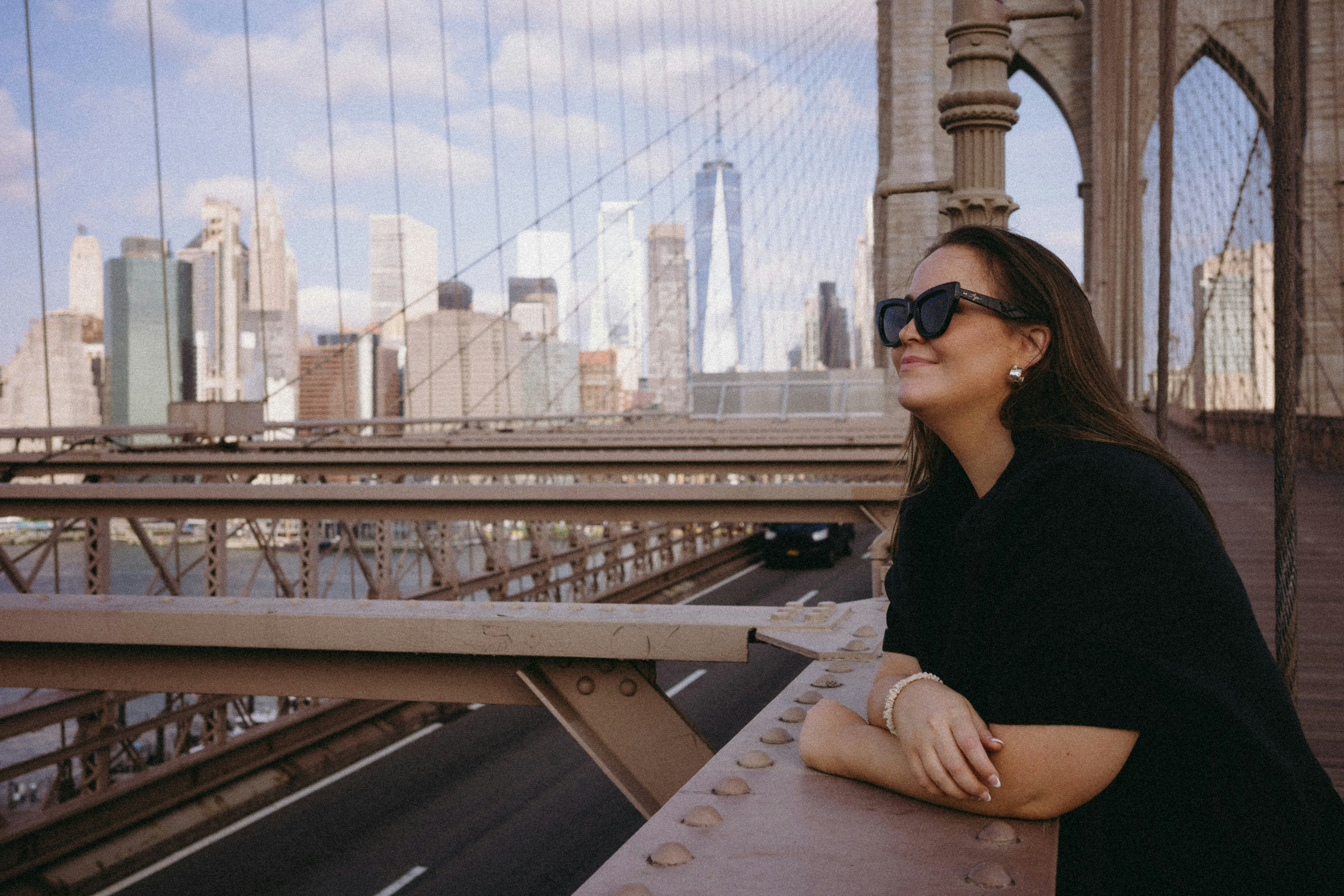 A woman standing on a bridge with a city in the background