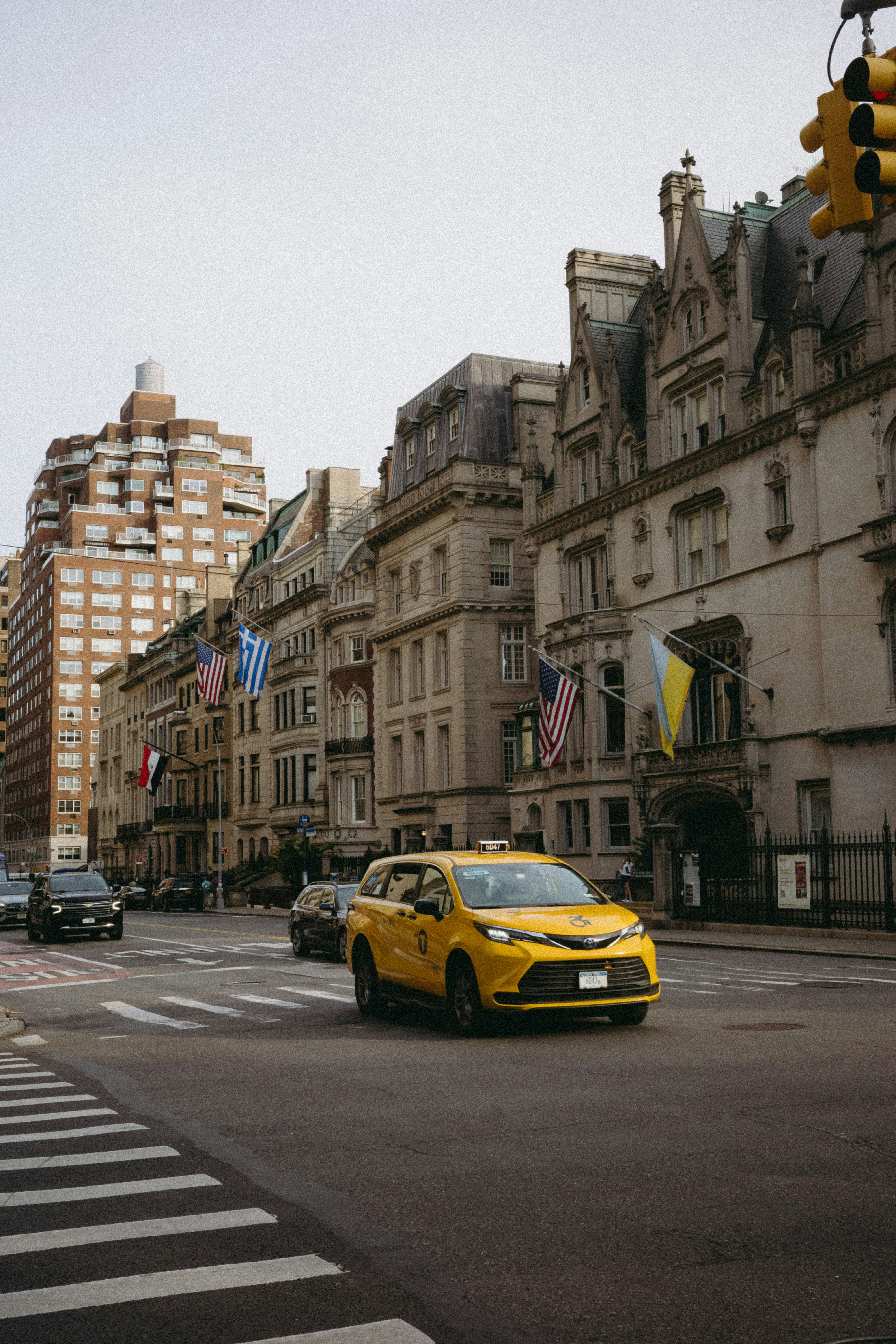 A yellow car driving down a street next to tall buildings