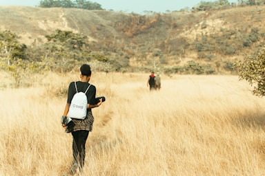 A couple of people walking through a dry grass field