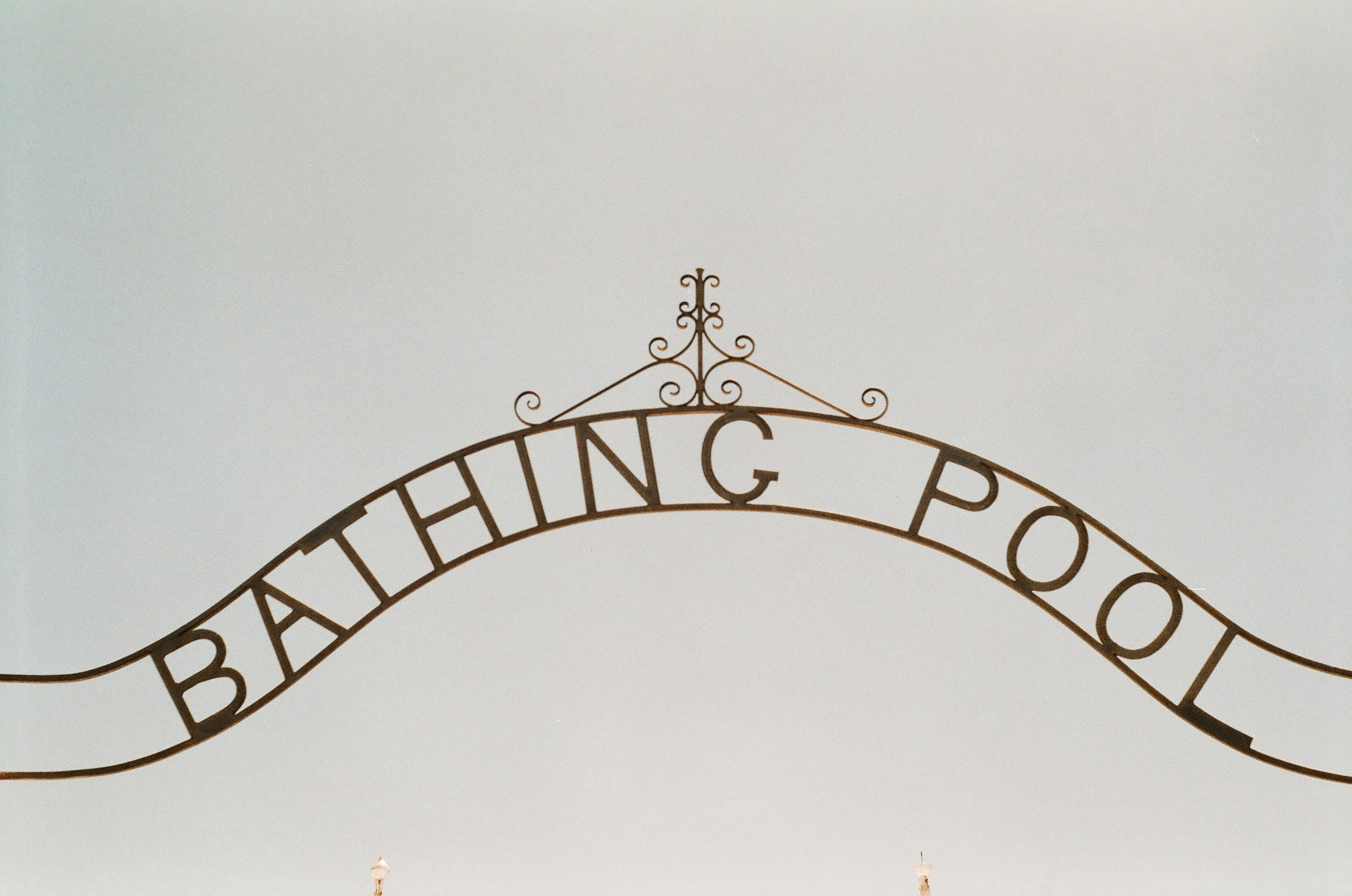 A sign that says bathing pool hanging from the side of a building