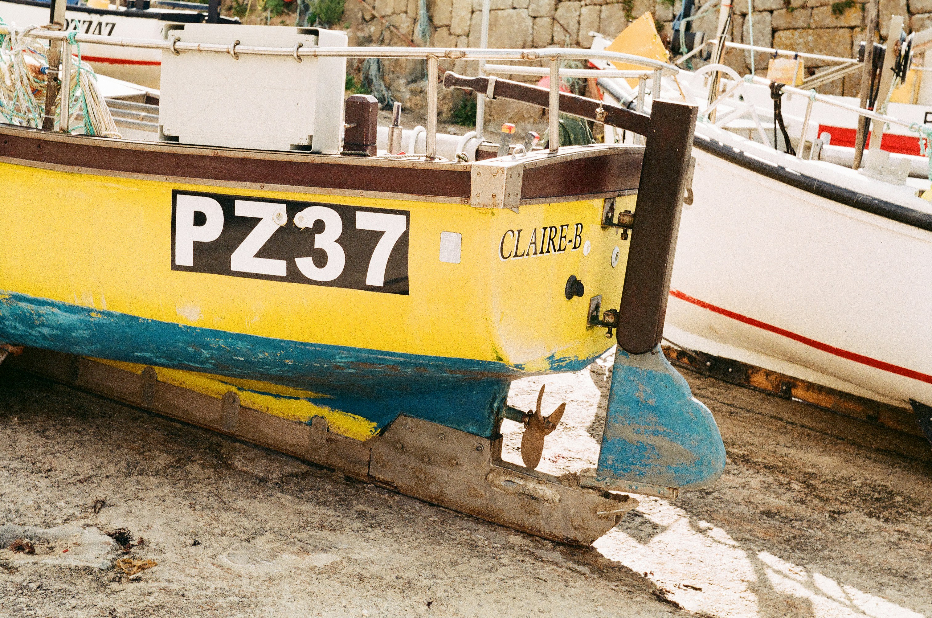A yellow boat sitting next to a white boat