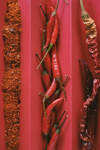 Three different types of chili peppers on a red background