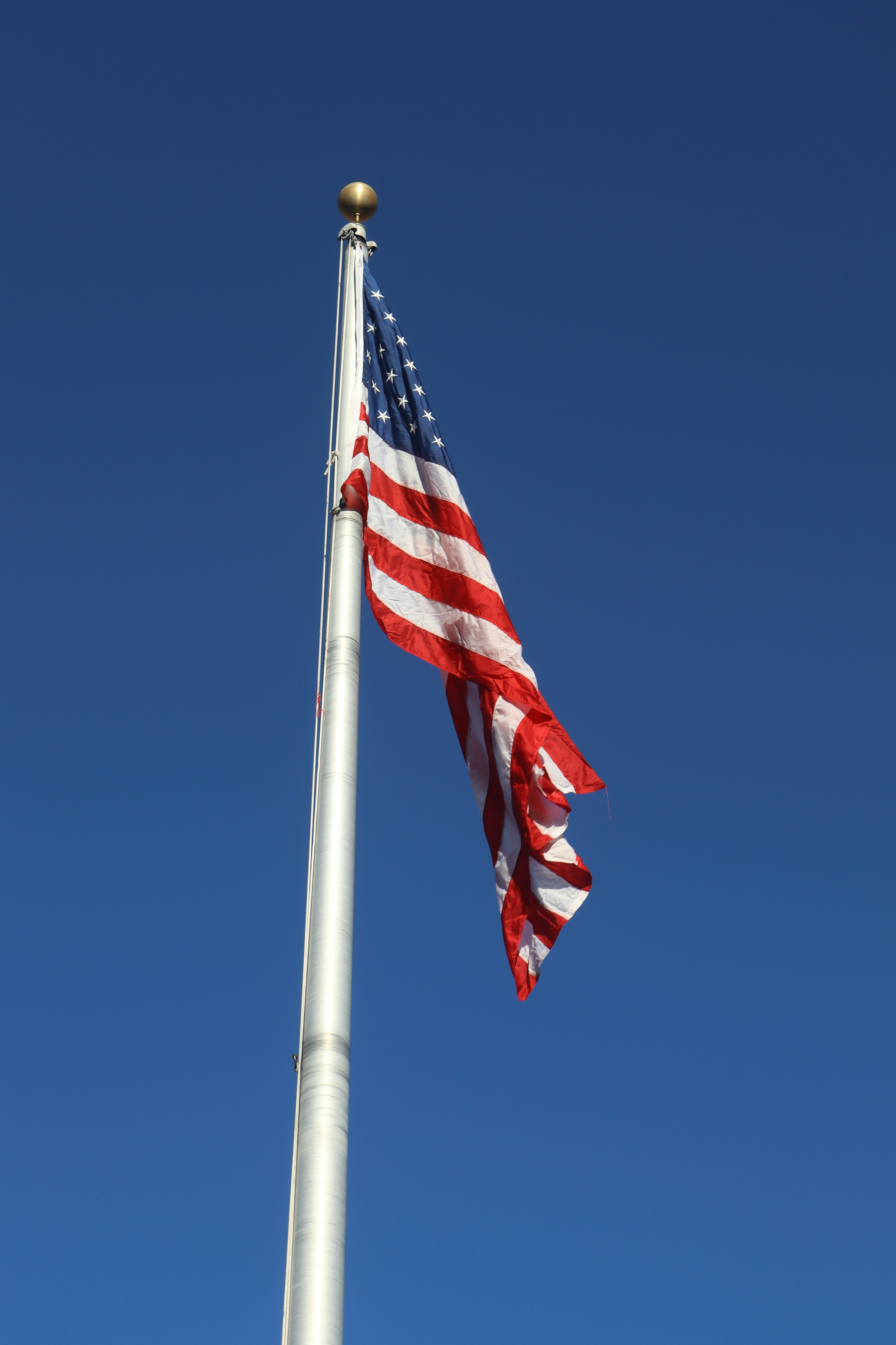 The american flag is flying high in the blue sky