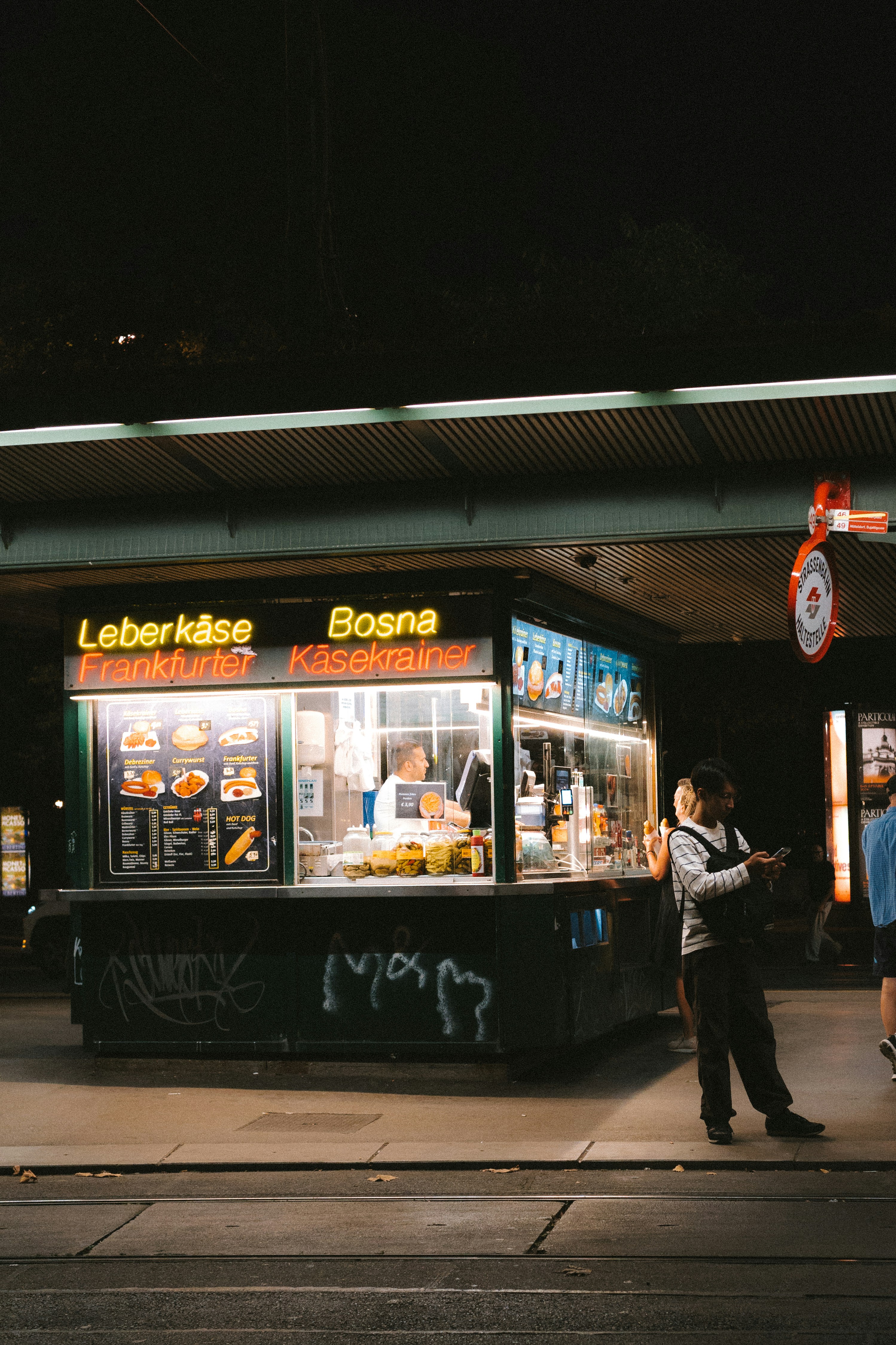 A couple of people standing outside of a food stand