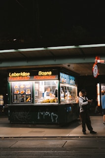 A couple of people standing outside of a food stand