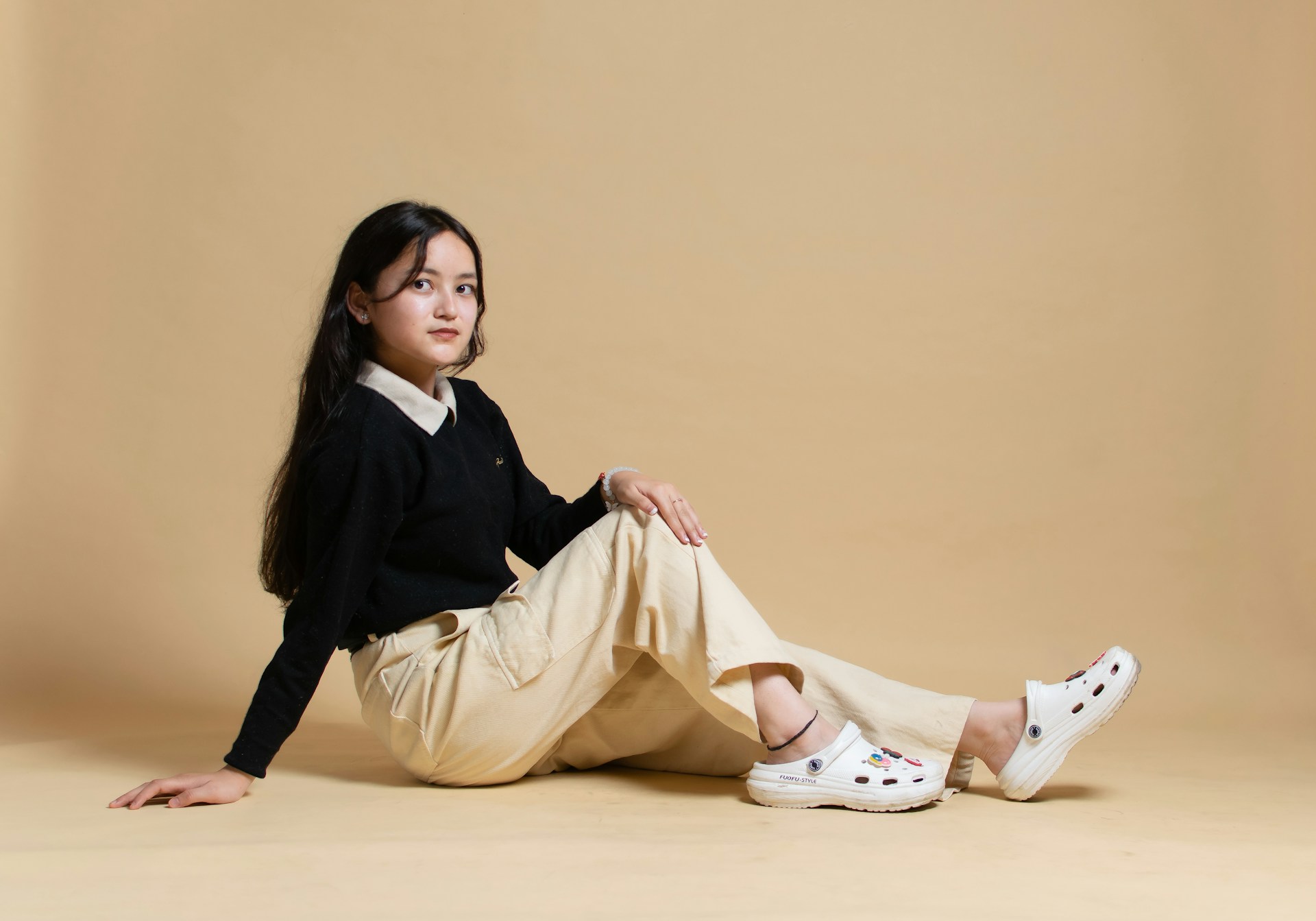 A little girl sitting on the floor with her legs crossed